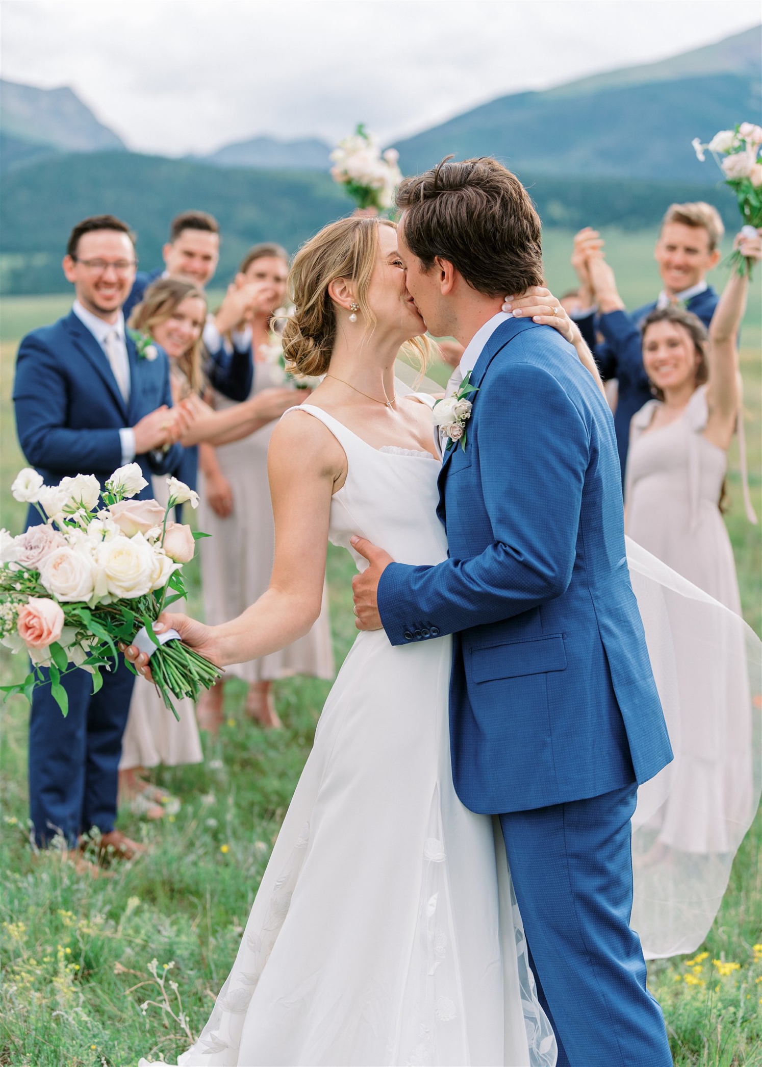 Bride and groom kissing while wedding party cheers | McArthur Weddings and Events
