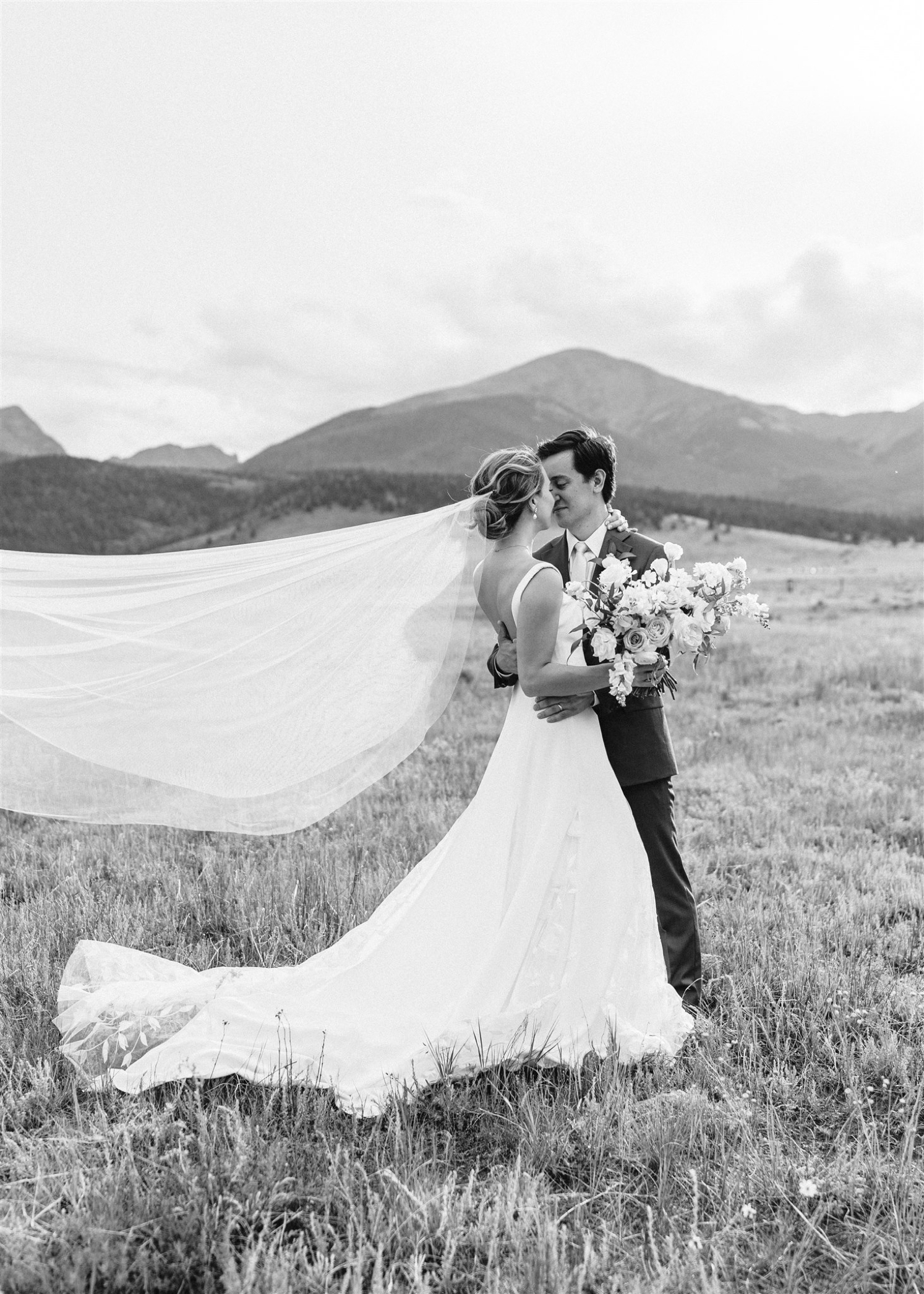 Bride and groom looking at each other with veil flowing in the wind | McArthur Weddings and Events