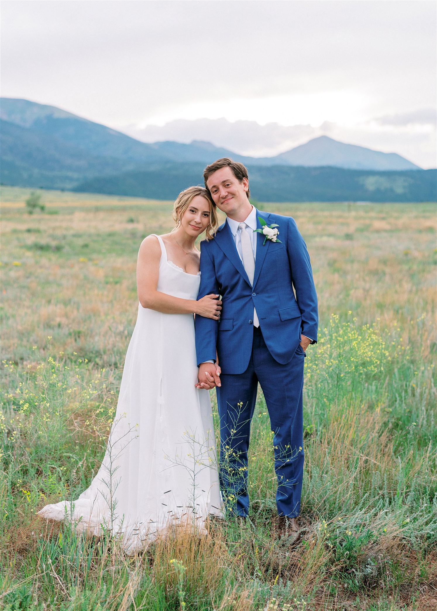 Bride and groom leaning into each other looking at camera | groom in blue suit at Three Peaks Ranch | McArthur Weddings and Events