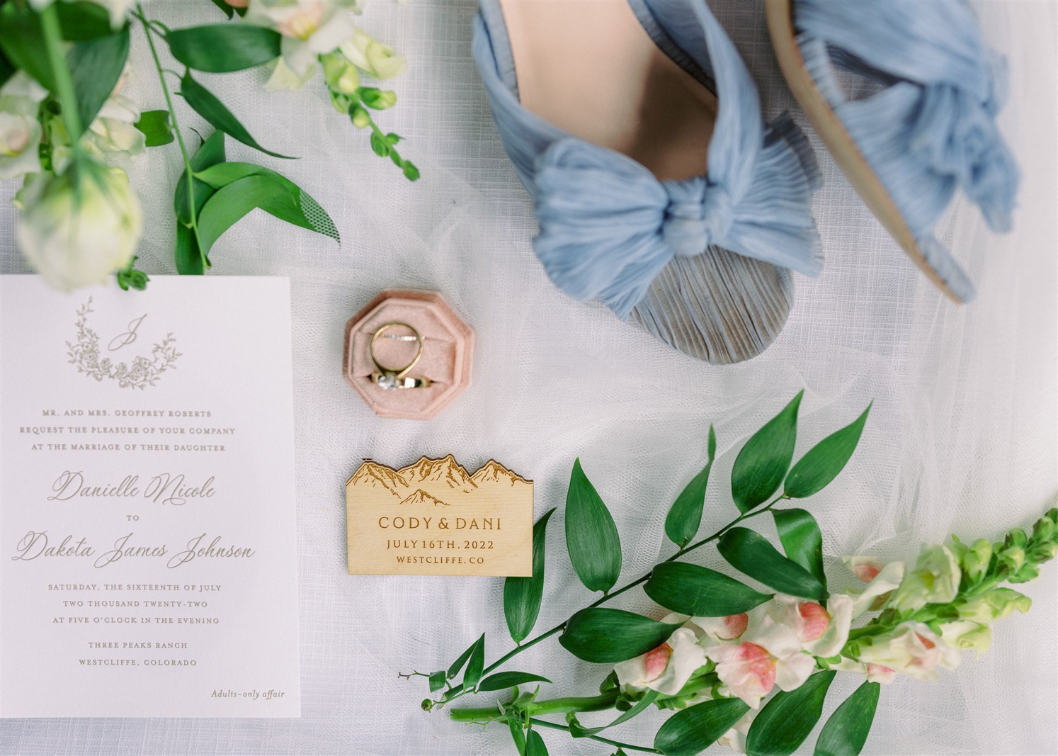 Wedding details photo with rings in pink box, light blue shoes, and wedding invitation | McArthur Weddings and Events