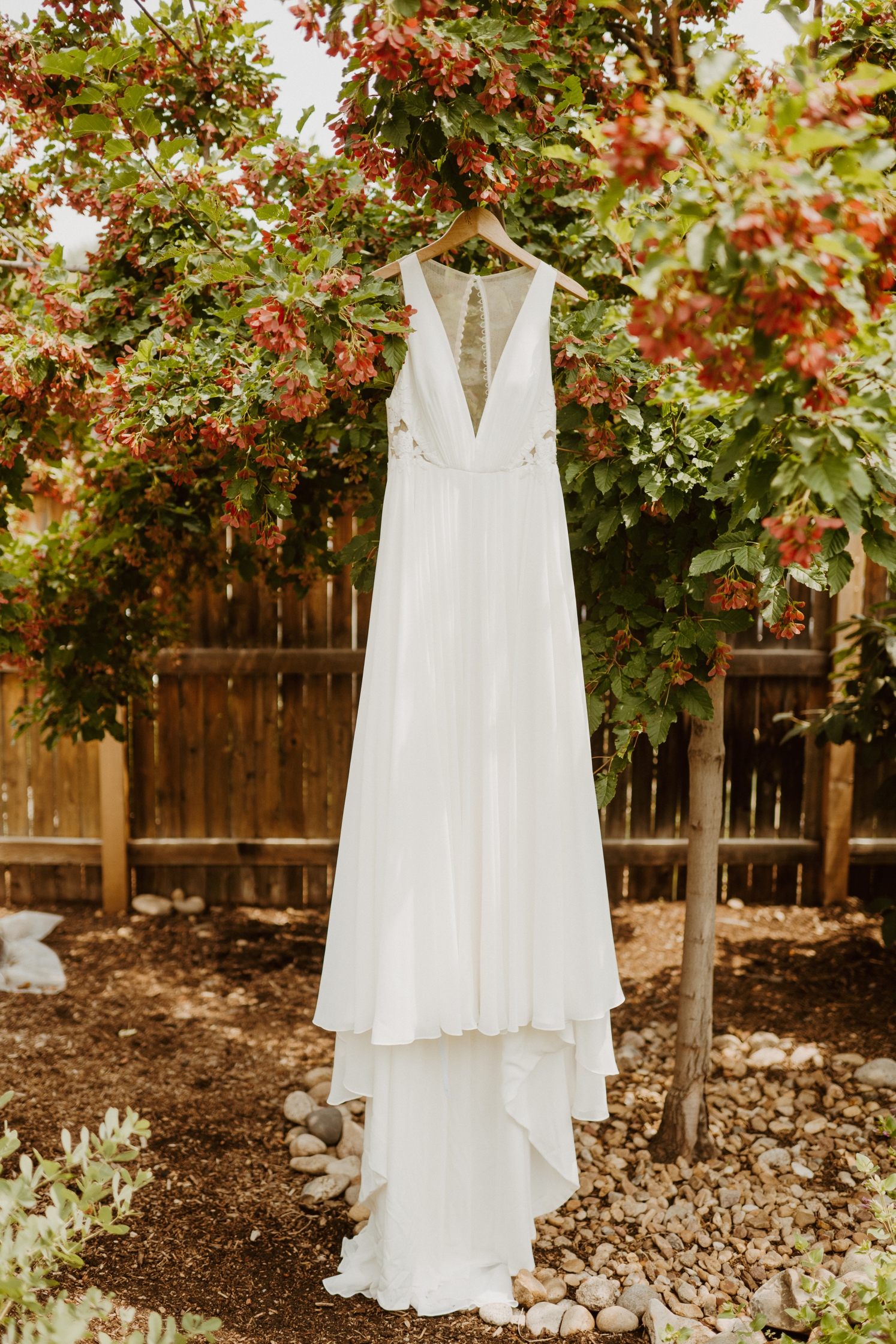 Deep v-neck wedding dress hanging outside from a tree | McArthur Weddings and Events
