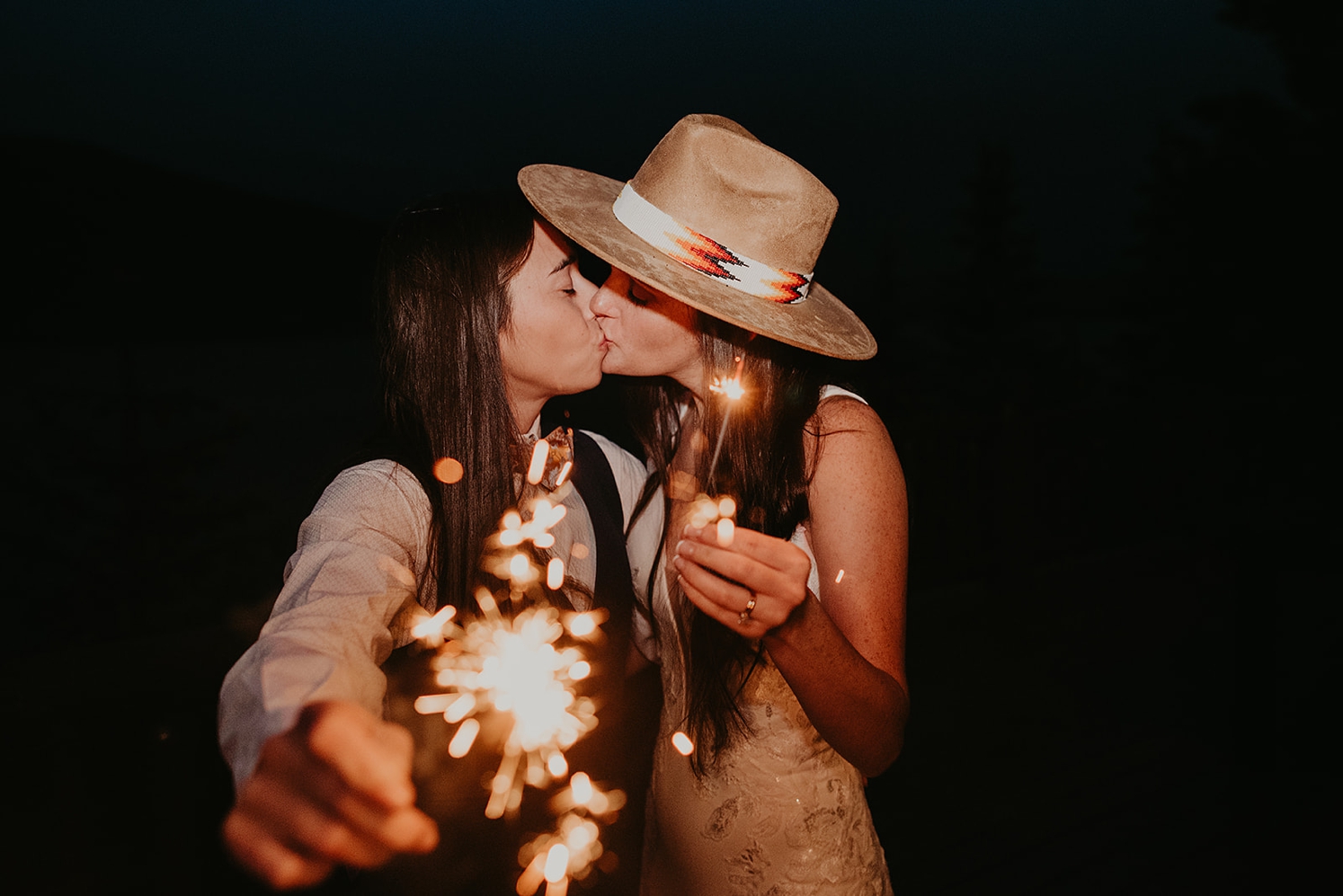 Couple kissing while holding sparklers at Colorado Airbnb wedding | McArthur Weddings and Events