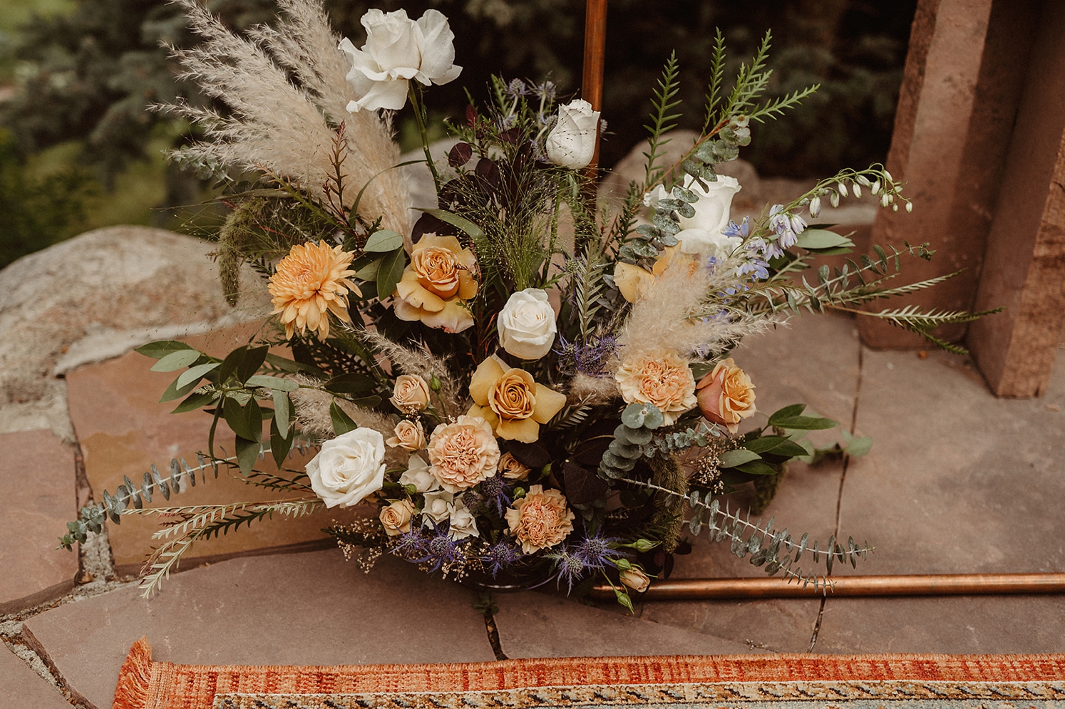 Muted peach flowers with pampas grass at ceremony arch at Colorado Airbnb wedding | McArthur Weddings and Events