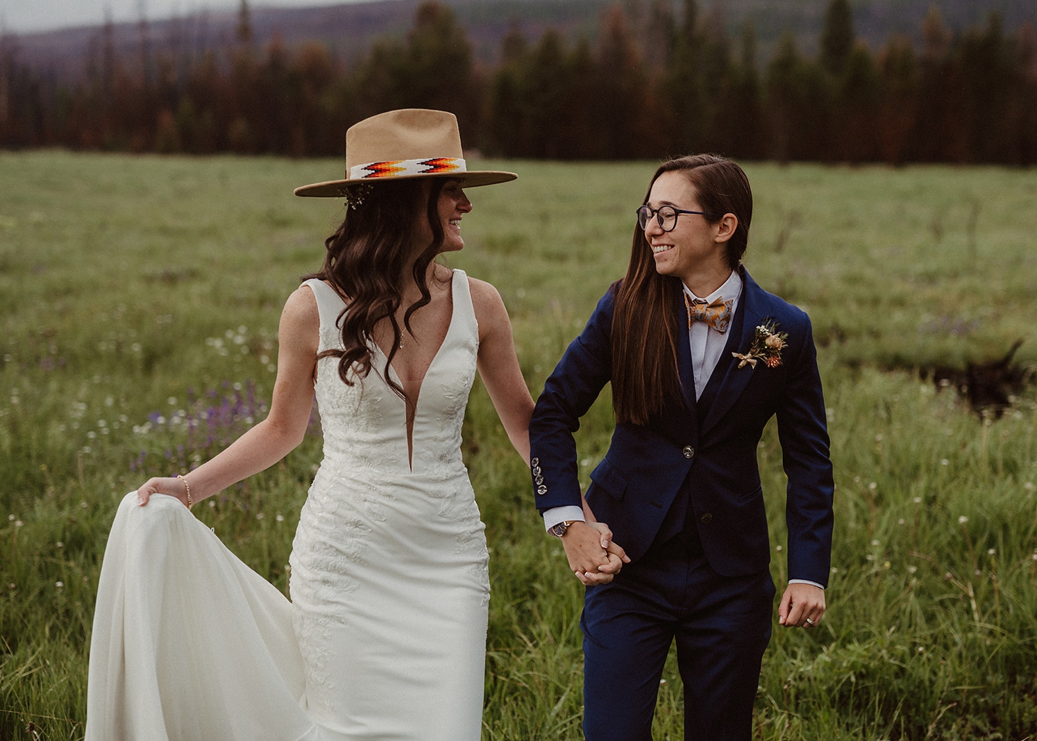 Couple holding hands and walking in field after ceremony at Colorado Airbnb wedding | McArthur Weddings and Events
