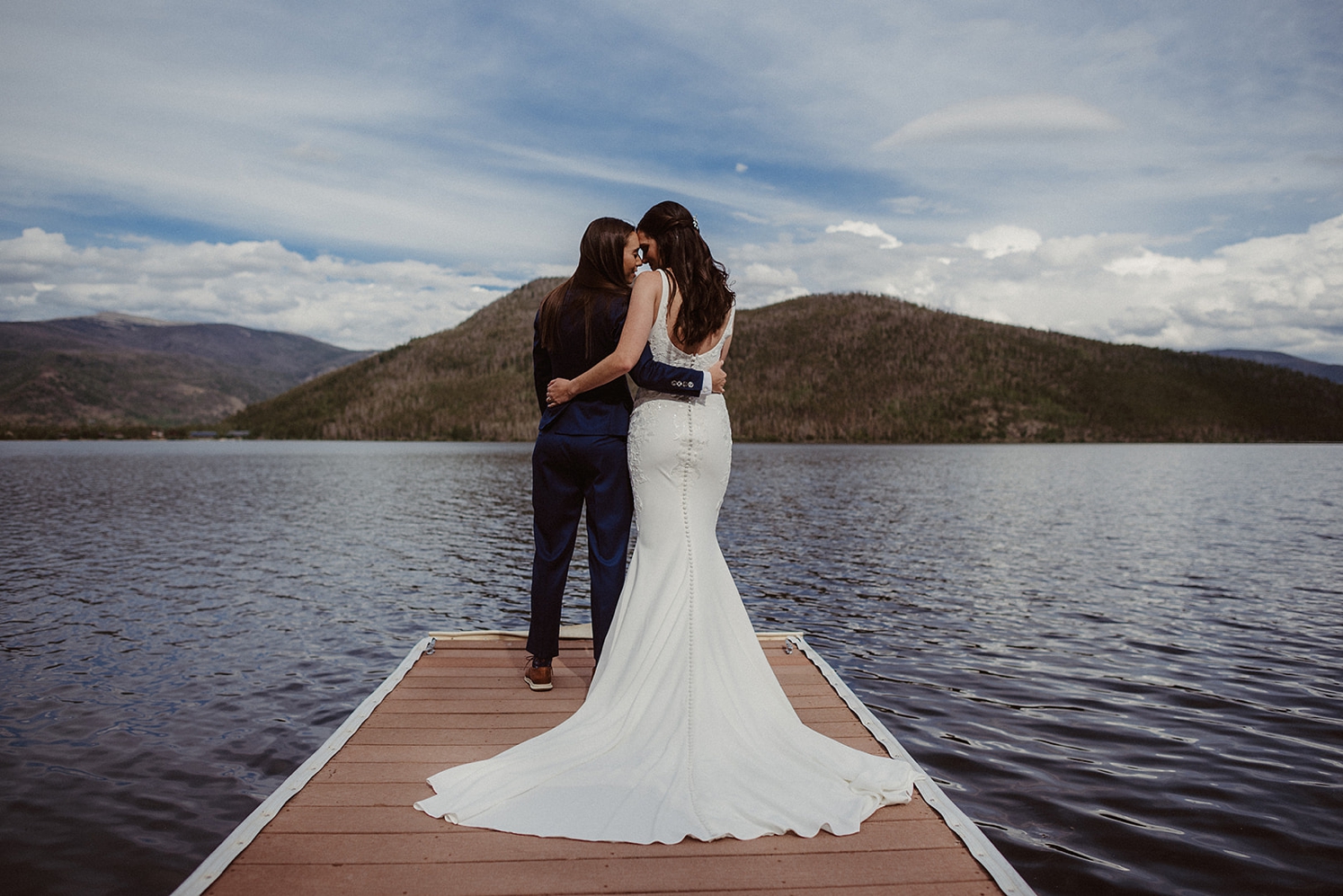 Couple standing on dock with arms around each other | McArthur Weddings and Events
