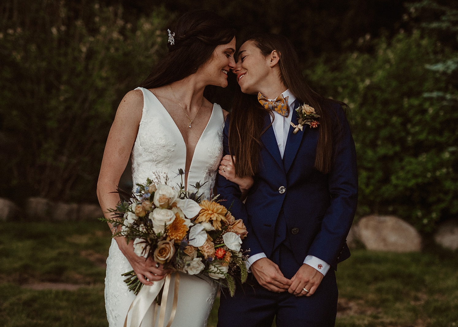 Couple looking at each other and smiling while partner holds bouquet | McArthur Weddings and Events