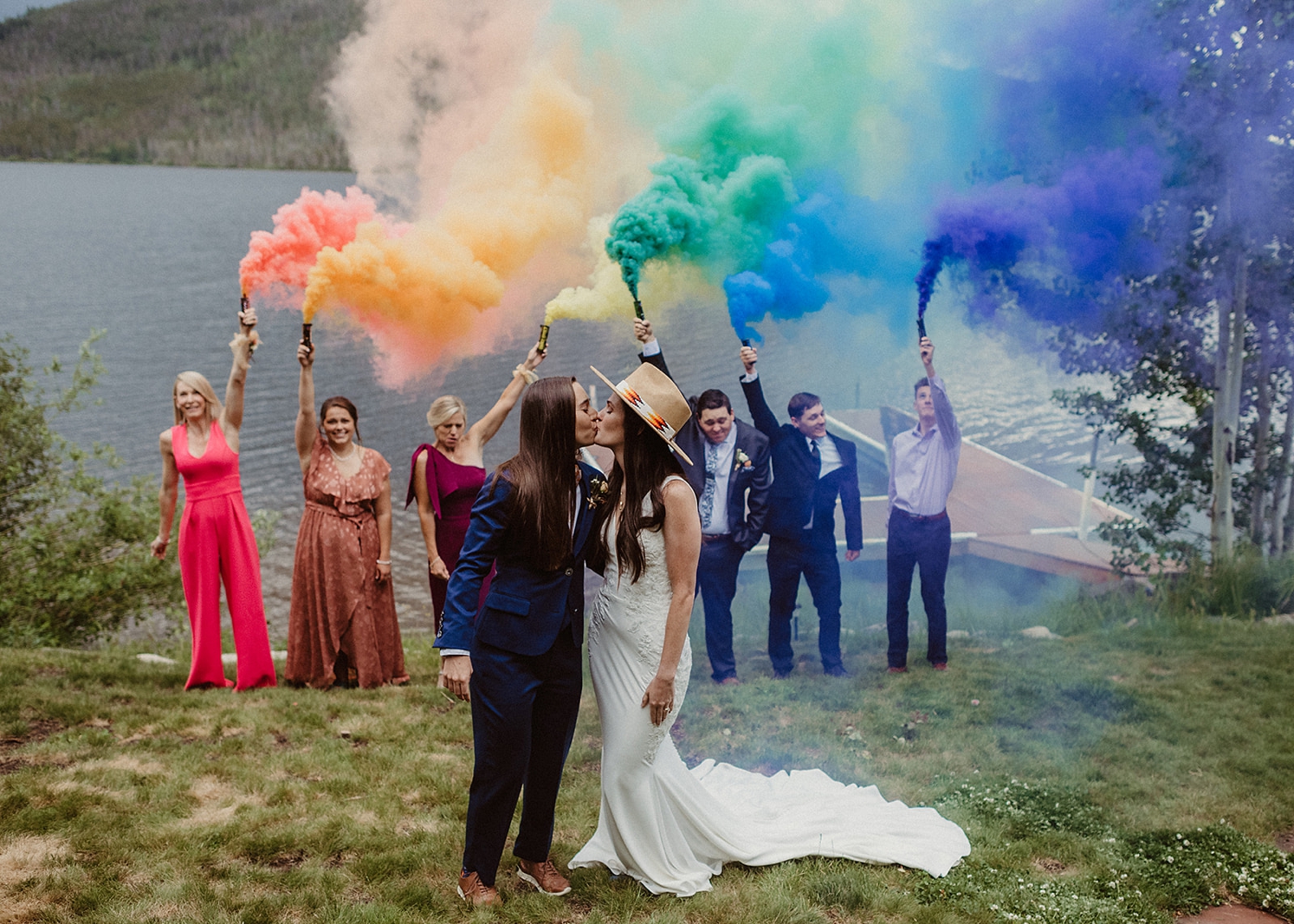 Couple kissing in front of rainbow smoke bombs to celebrate gay pride at Colorado Airbnb wedding | McArthur Weddings and Events