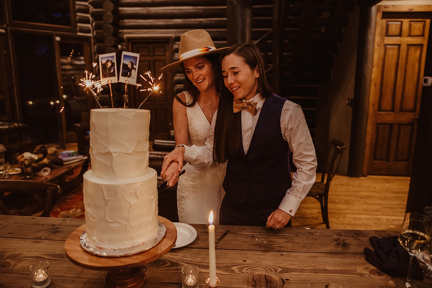 Partners cutting wedding cake with polaroids and sparkers on top of cake | McArthur Weddings and Events