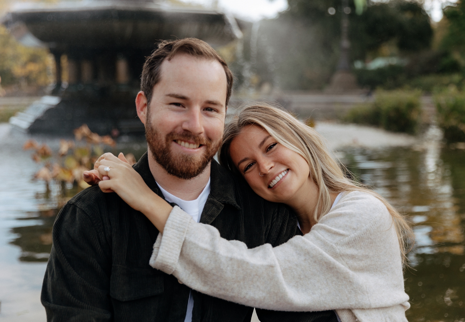Woman resting head on her fiancé in front of fountain at Central Park engagement shoot | McArthur Weddings and Events