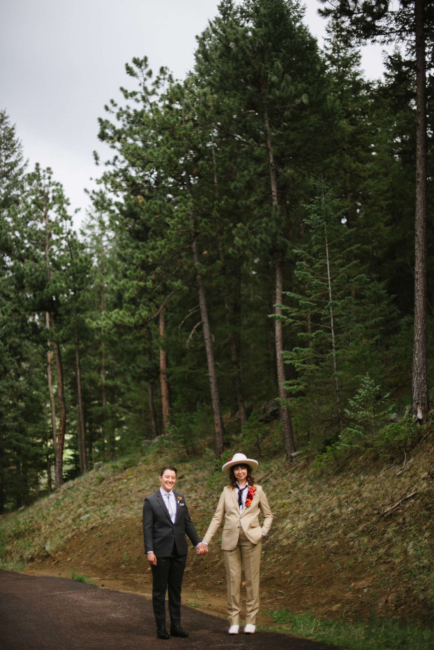 LBGTQ couple standing on asphalt road in front of forest | McArthur Weddings and Events