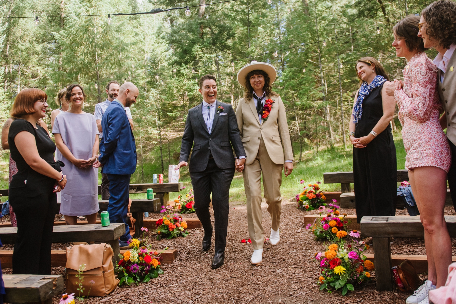 Couple holding hands and walking down aisle at LGBTQ wedding ceremony | McArthur Weddings and Events