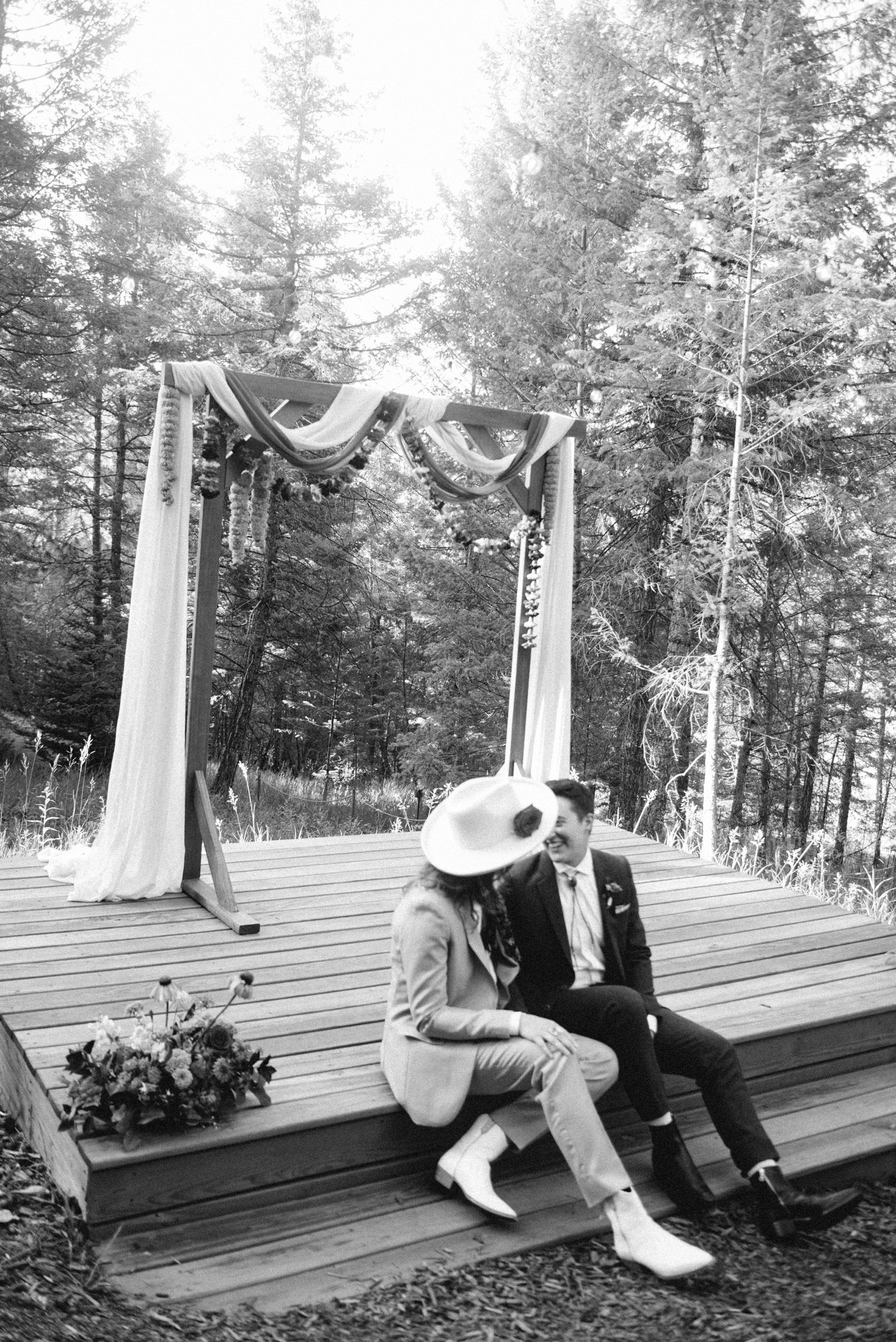 Couple sitting on ceremony altar while looking at each other | McArthur Weddings and Events