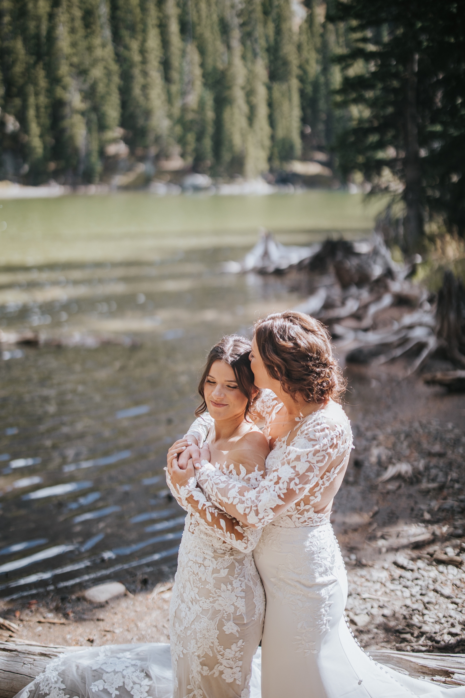 Partner kissing partner's head in front of lake at Telluride wedding | McArthur Weddings and Events