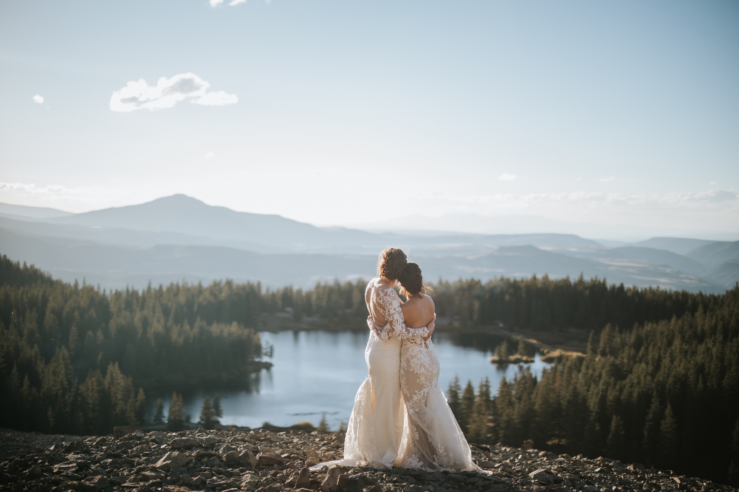 Brides embracing and looking down at lake at The Observatory at Alta Lakes | McArthur Weddings and Events