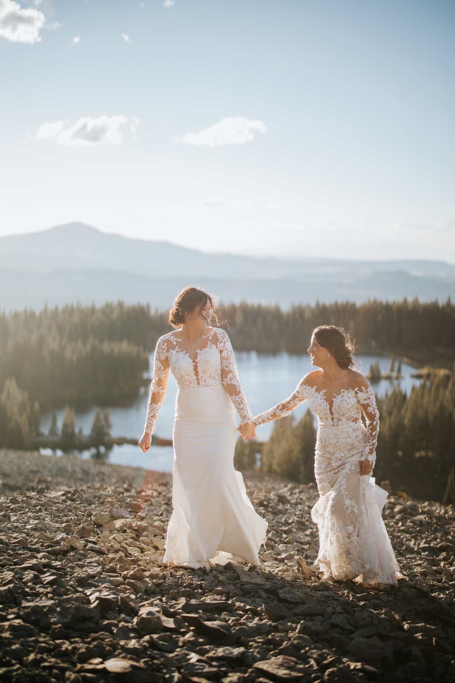 Brides holding hands and walking up mountain at Telluride wedding | McArthur Weddings and Events