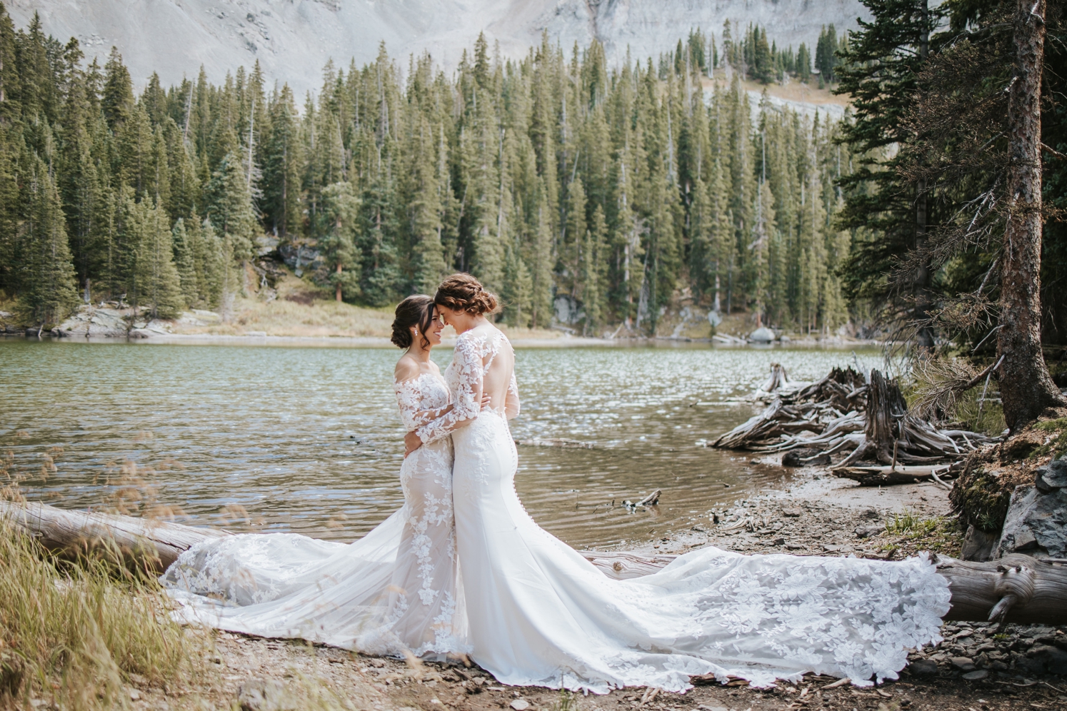 Brides facing each other and standing next to lake at Telluride wedding | McArthur Weddings and Events
