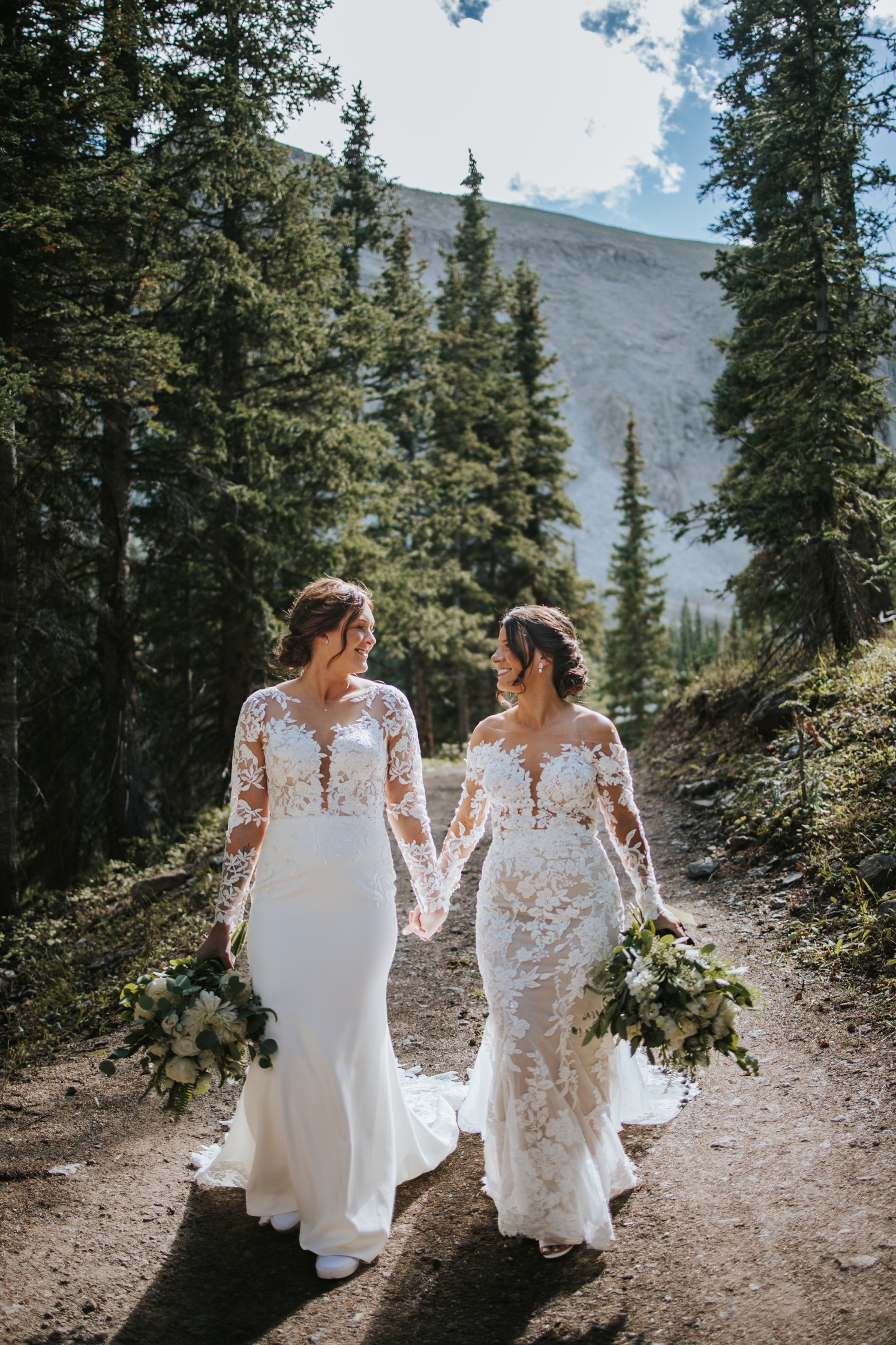 Brides holding hands and walking down dirt road after Telluride wedding | McArthur Weddings and Events