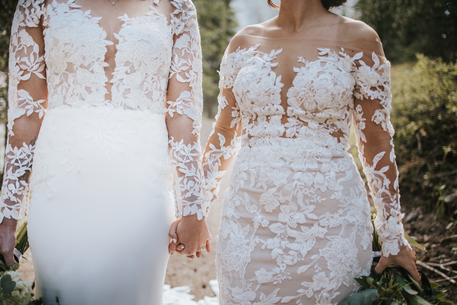 Brides wearing lace gowns holding hands and walking | McArthur Weddings and Events