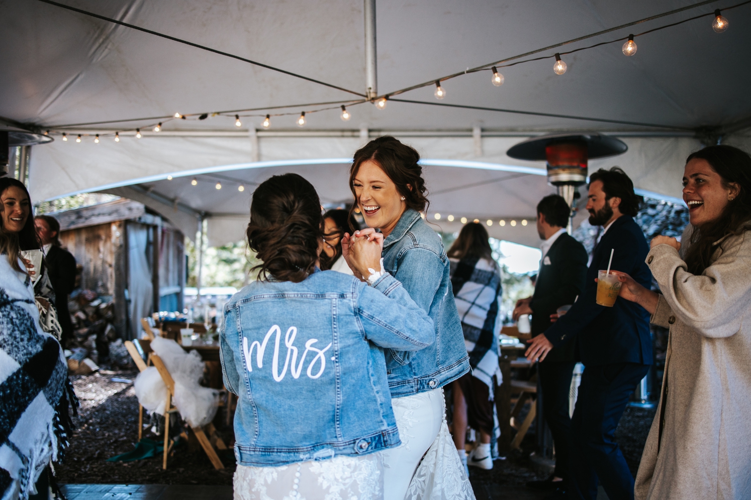 Brides wearing denim jackets and dancing at wedding reception | McArthur Weddings and Events