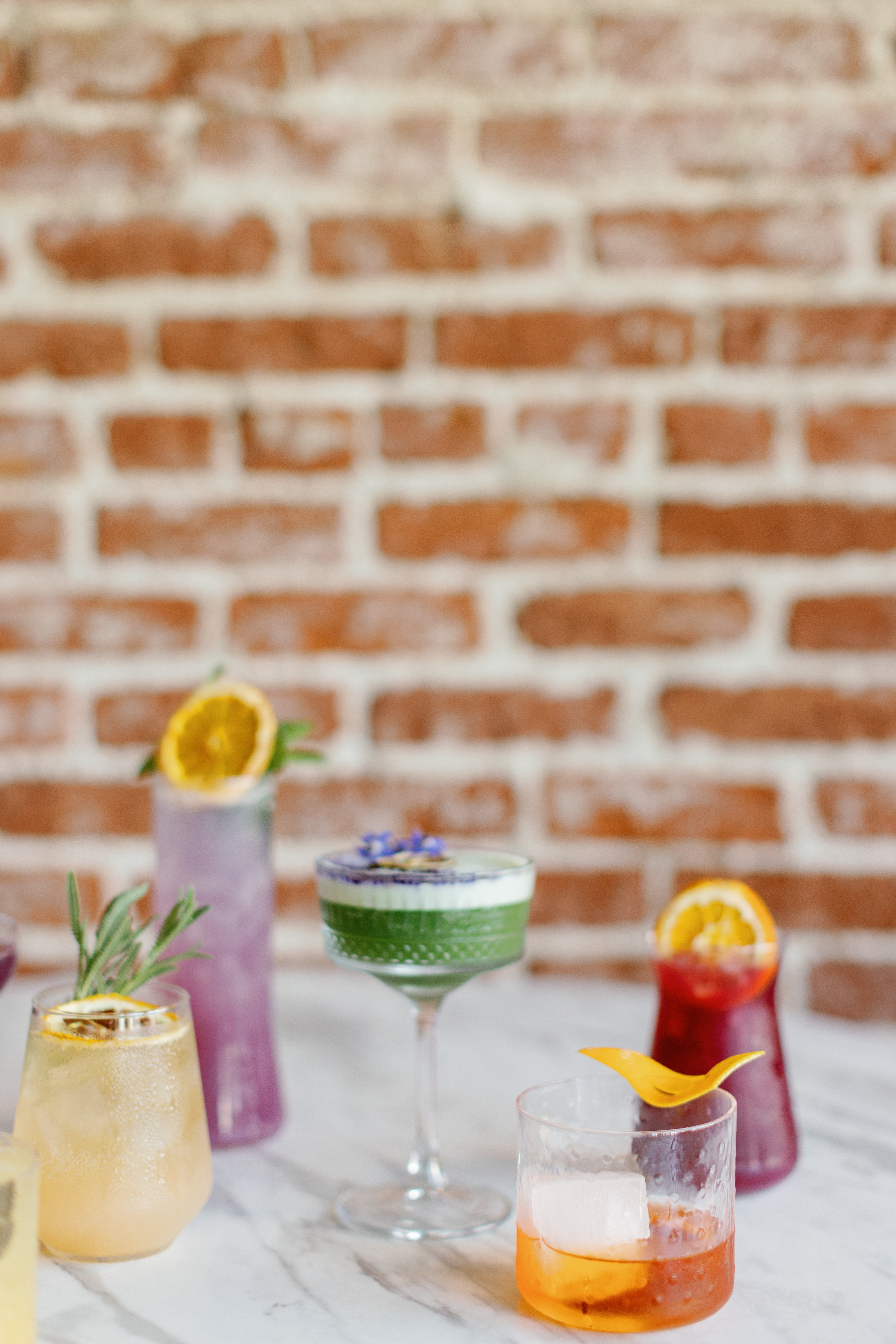 Specialty cocktails on a table in front of a brick wall | McArthur Weddings and Events