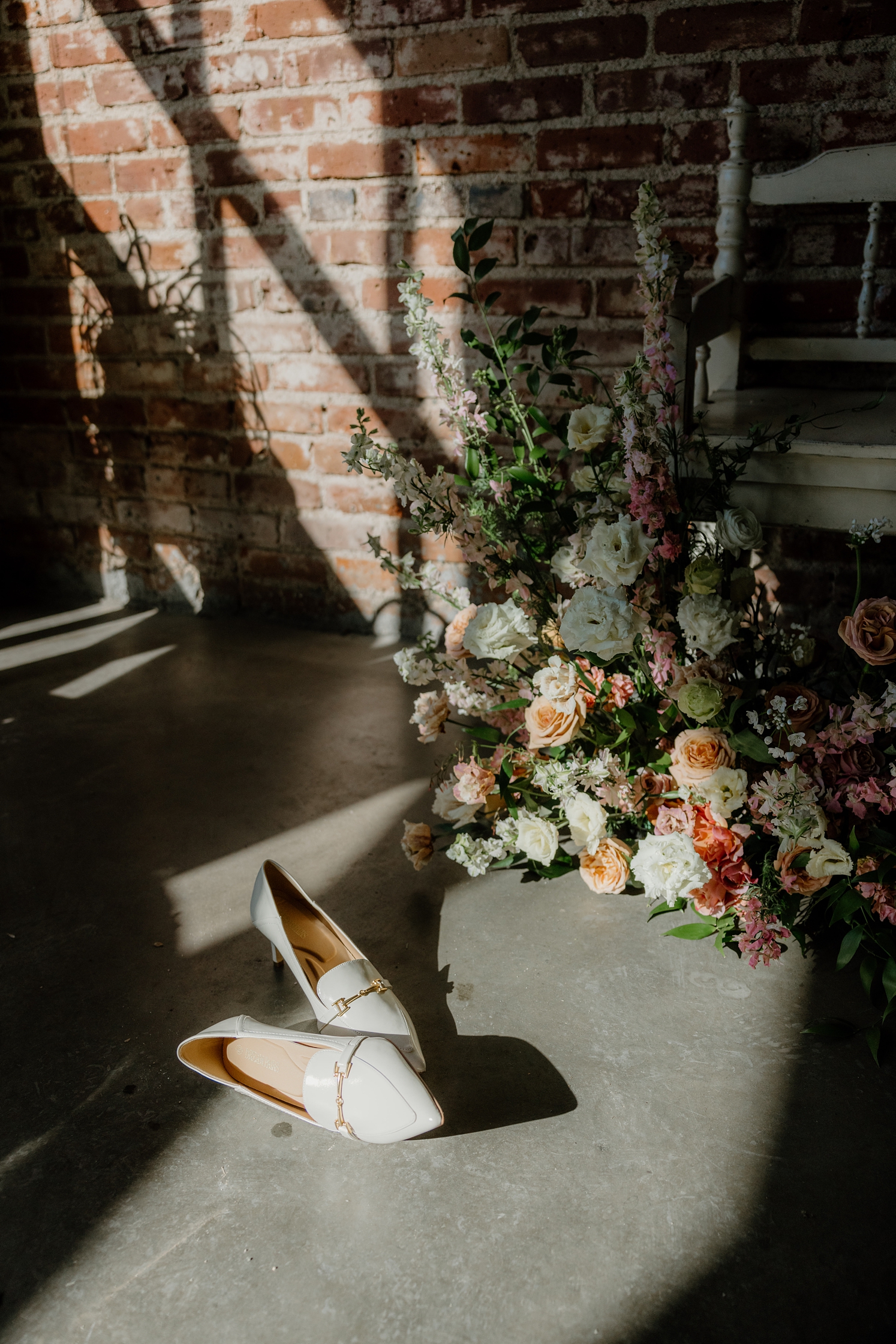 White wedding shoes next to pink and white floral arrangement | McArthur Weddings and Events