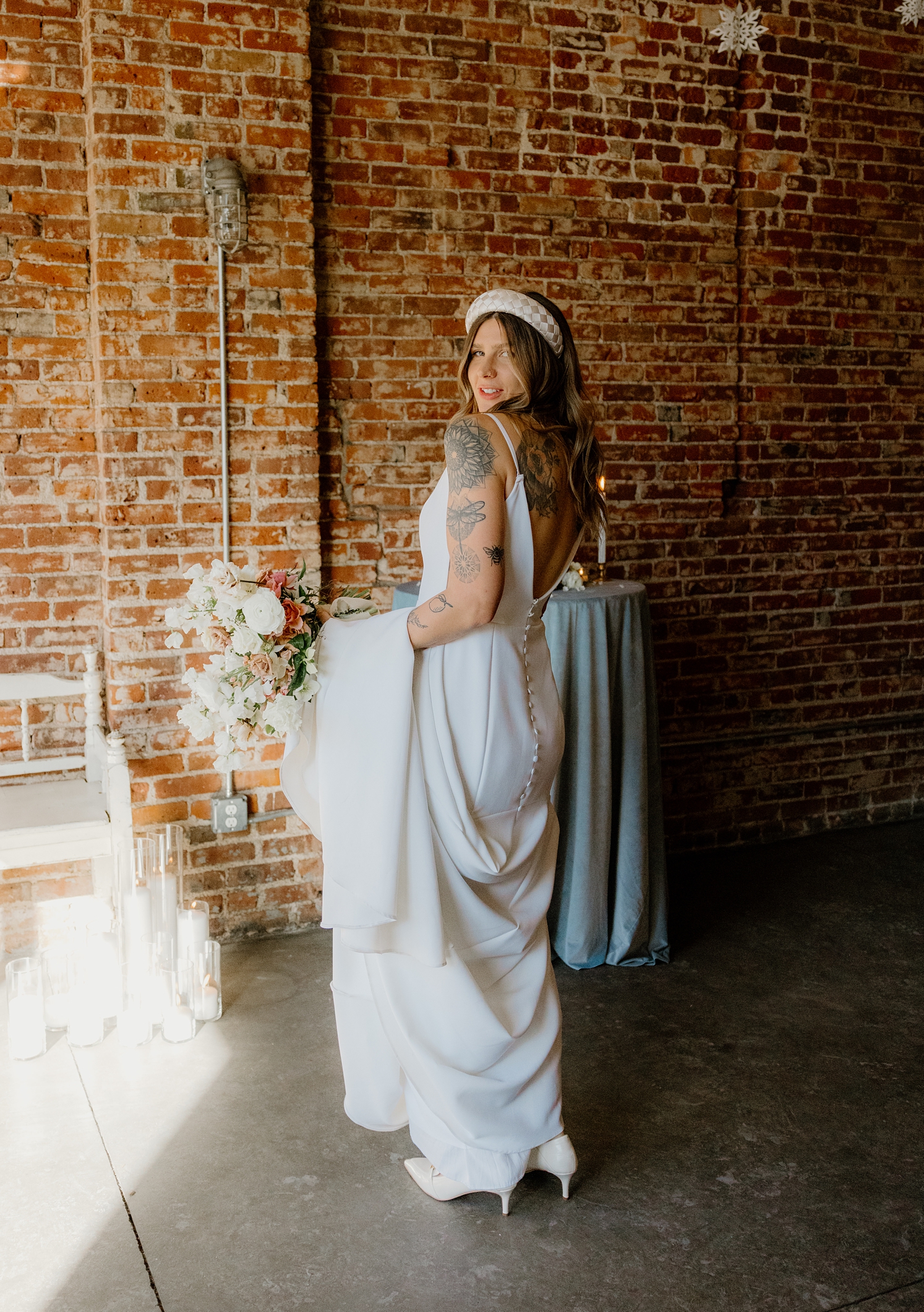 Bride looking over her shoulder while holding dress train over her arm | McArthur Weddings and Events