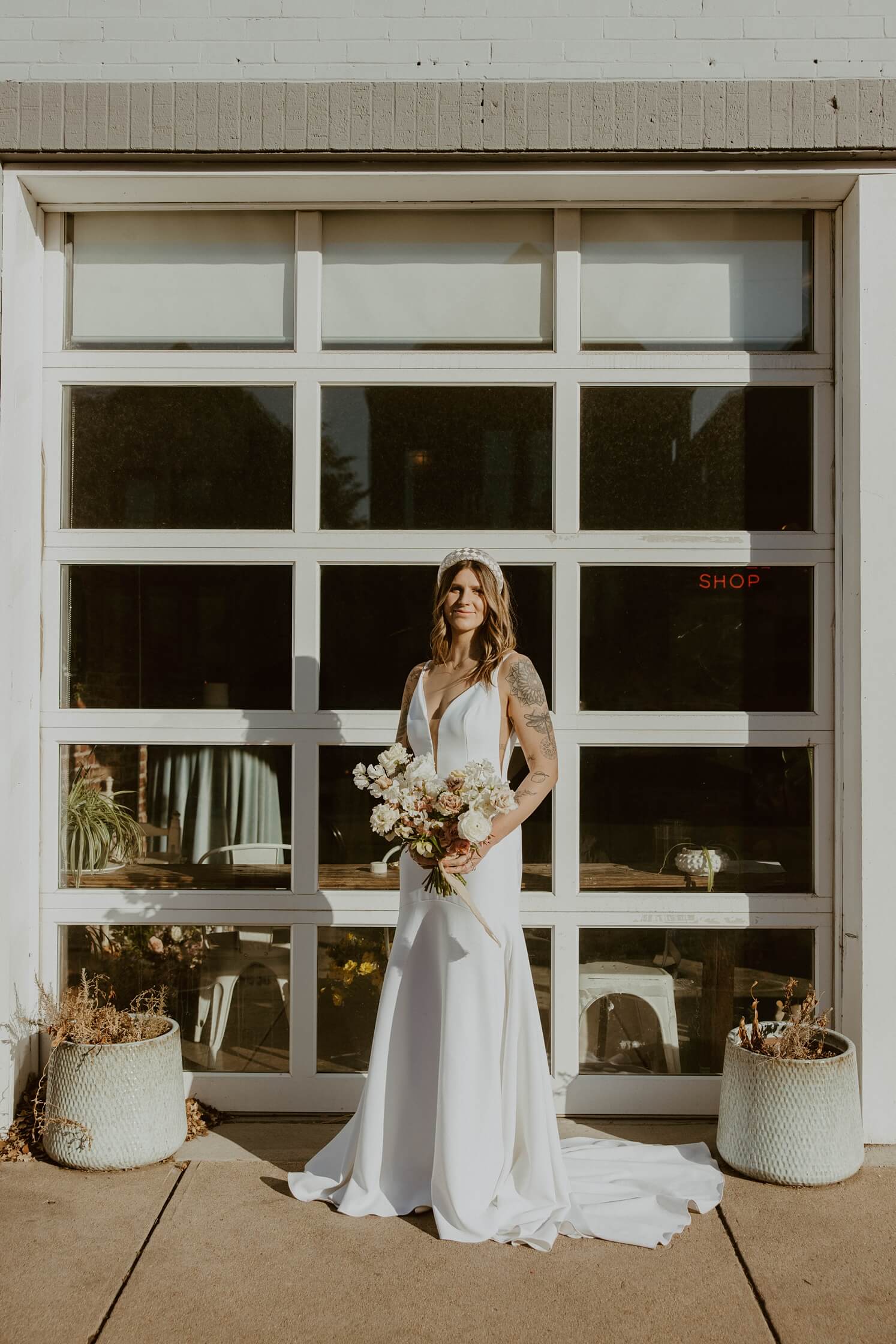 Bride standing in front of garage door at Queenbury Rules Coffee House | McArthur Weddings and Events