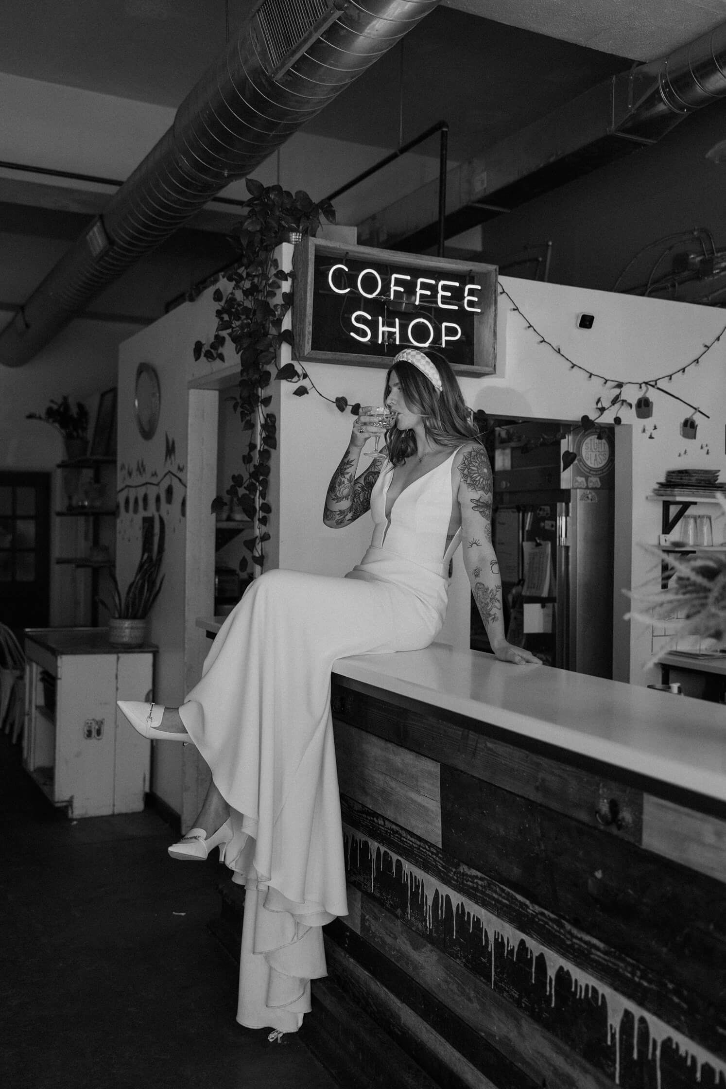 Woman sitting on bar at Queensberry Rules Coffee House drinking champagne | McArthur Weddings and Events