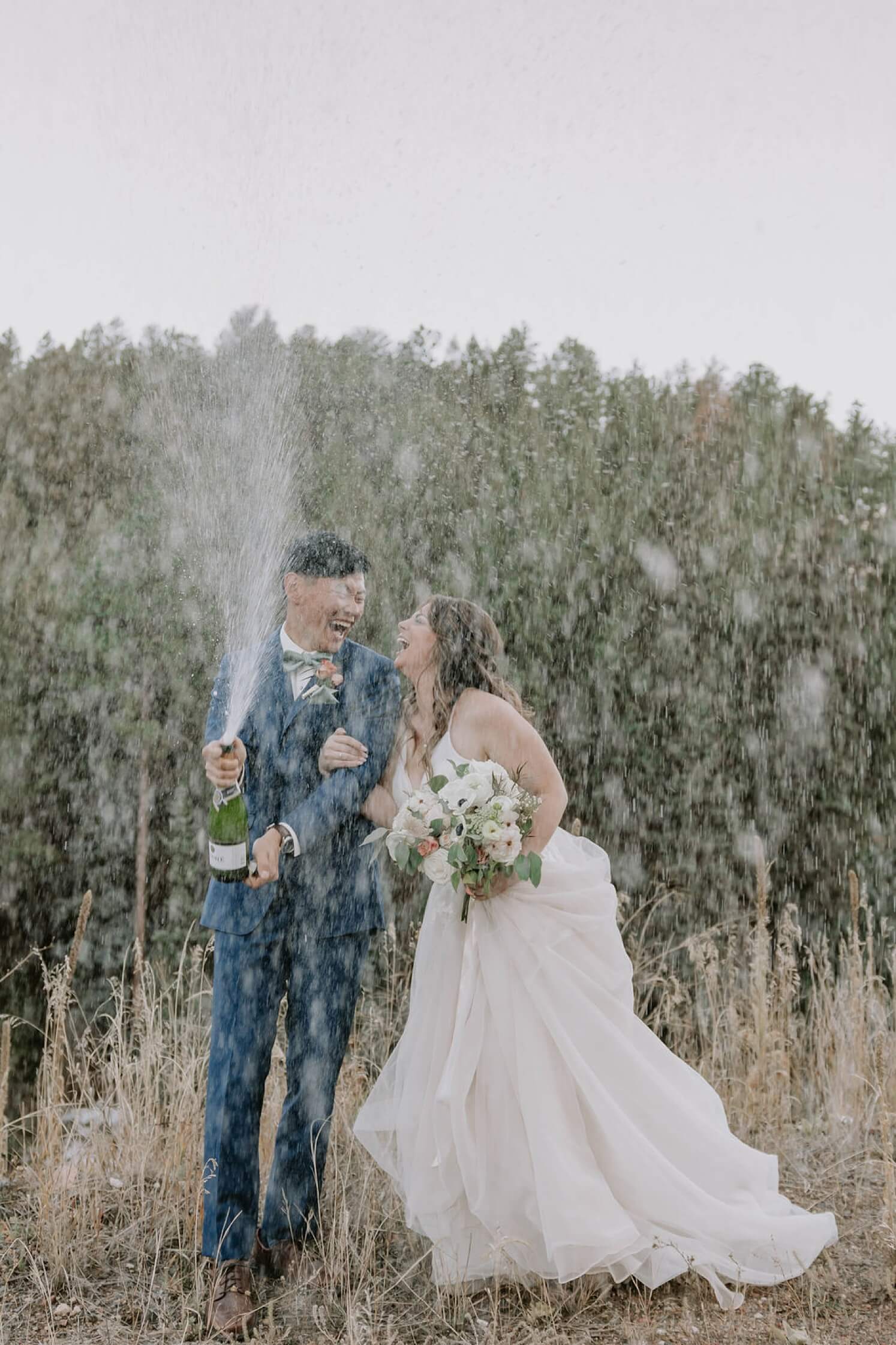Bride and groom popping a bottle of champagne after Colorado elopement | McArthur Weddings and Events