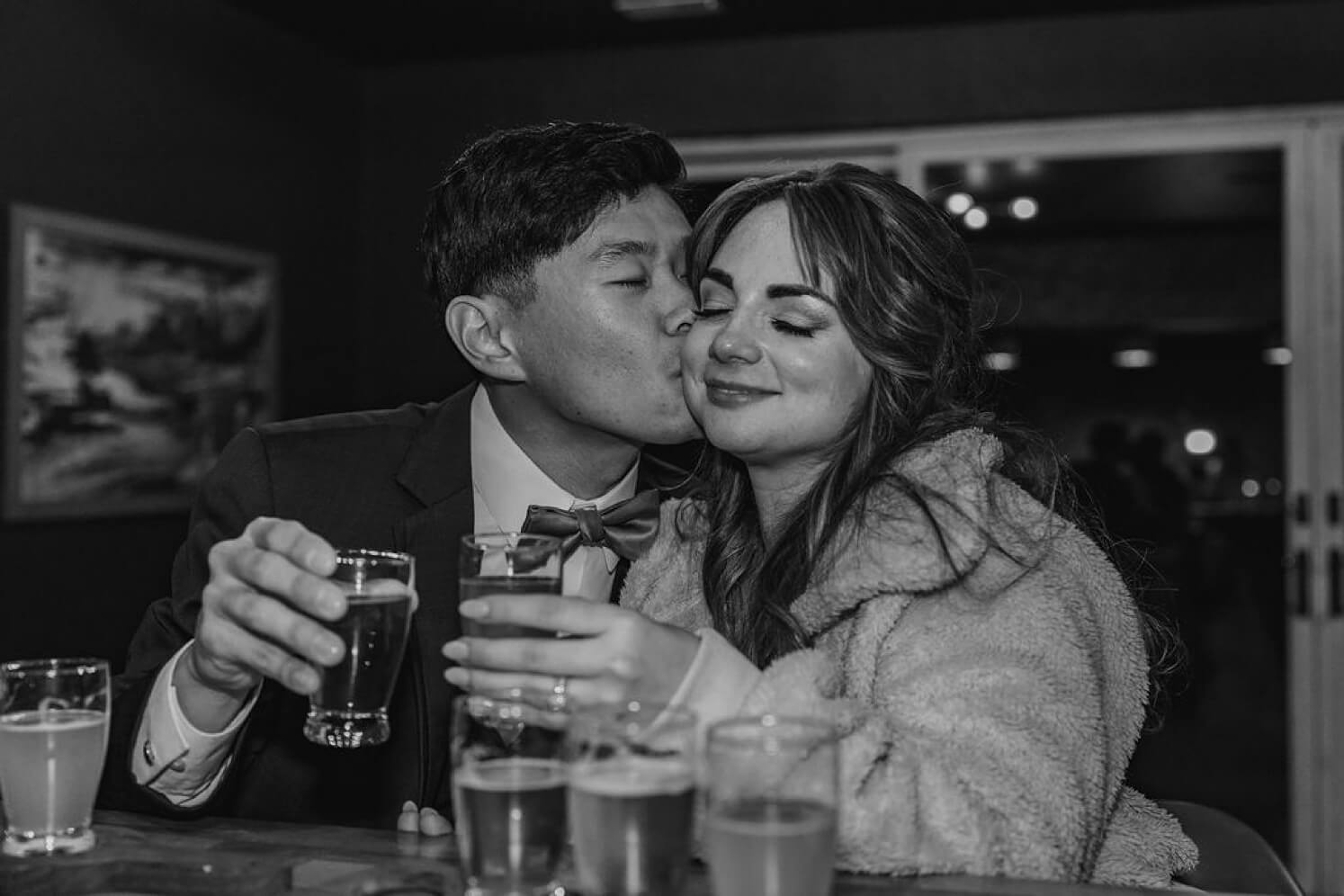 Groom kissing bride's cheek during beer tasting at Colorado elopement | McArthur Weddings and Events