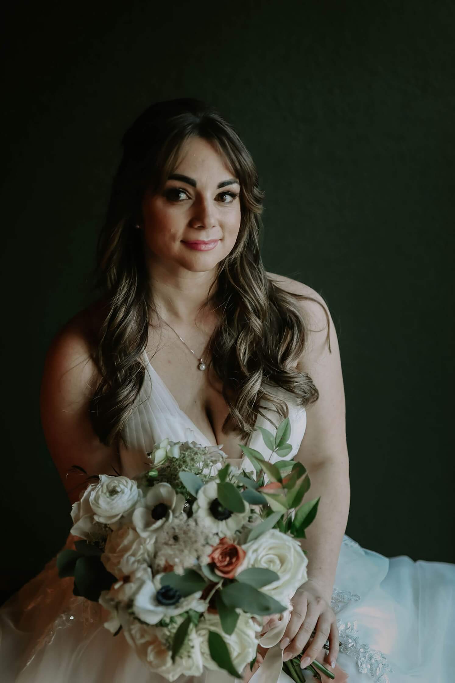 Bride wearing a v-neck wedding dress holding a white and coral wedding bouquet | McArthur Weddings and Events