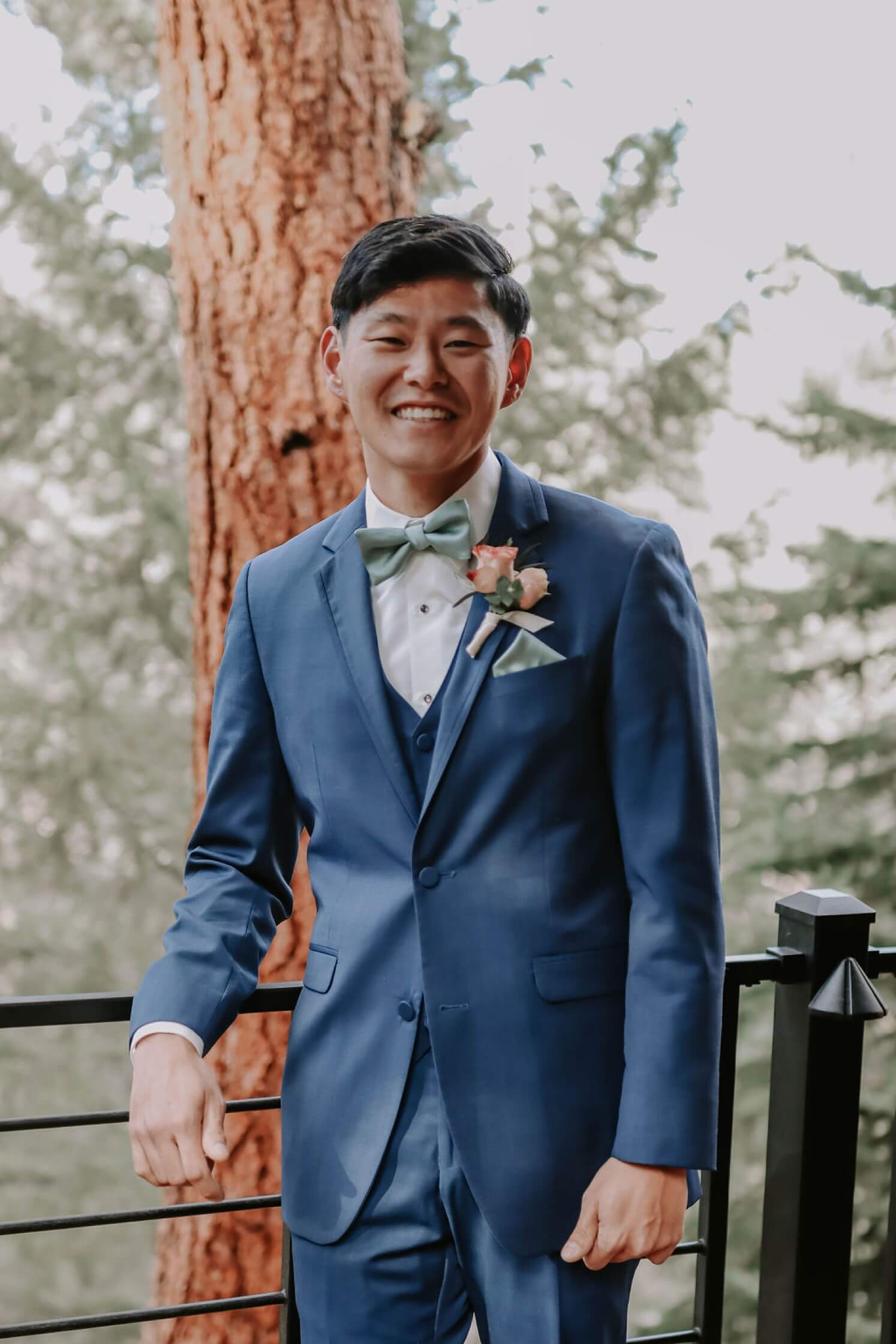 Groom wearing blue suit standing on deck at Juniper Mountain House | McArthur Weddings and Events
