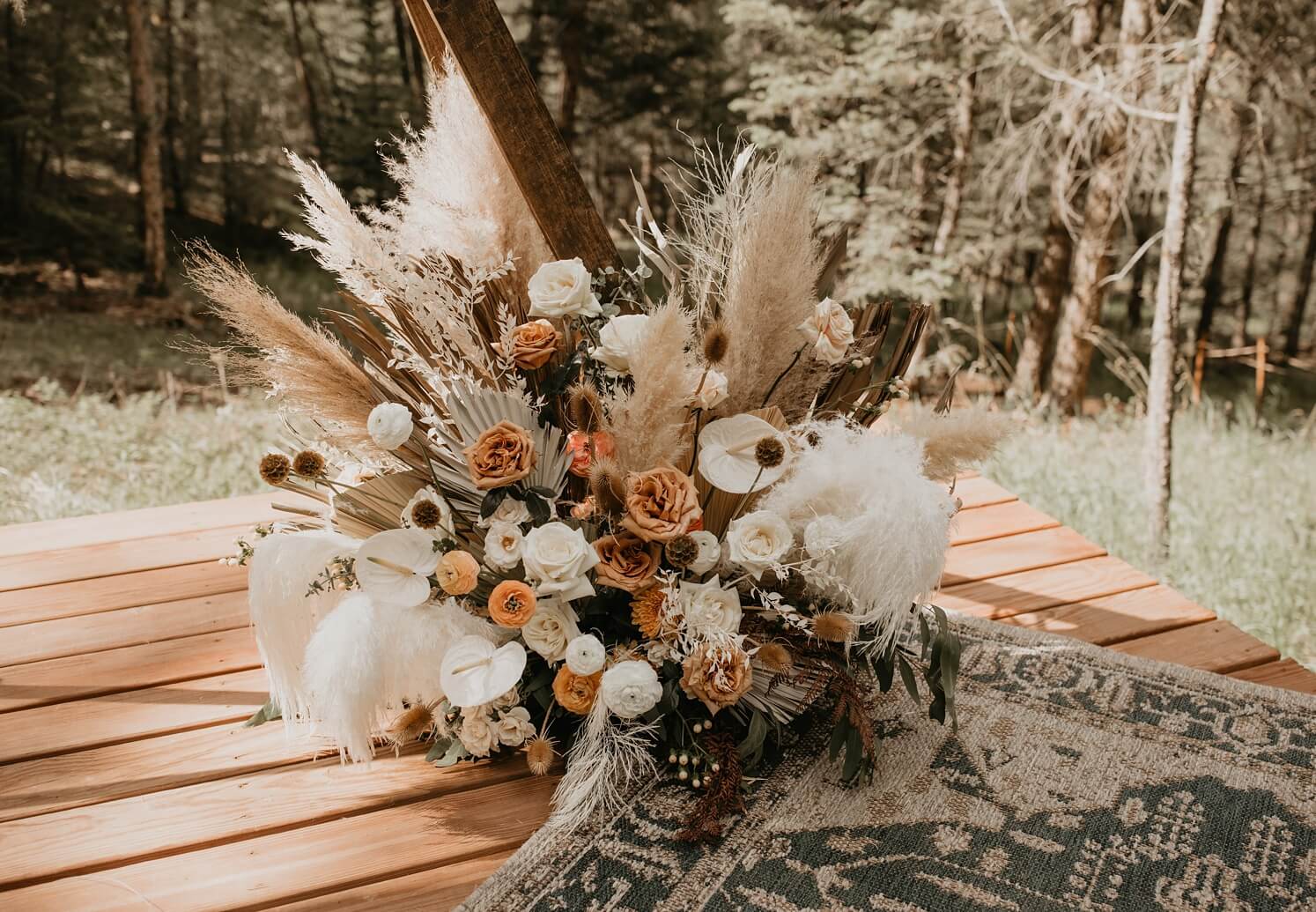 Wedding floral design: boho ceremony florals with pampas grass, fan leaves, and white and burnt orange flowers | McArthur Weddings and Events