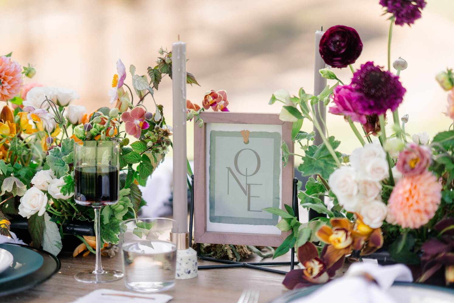 Table number sign in pink frame surrounded by candles and flowers | McArthur Weddings and Events