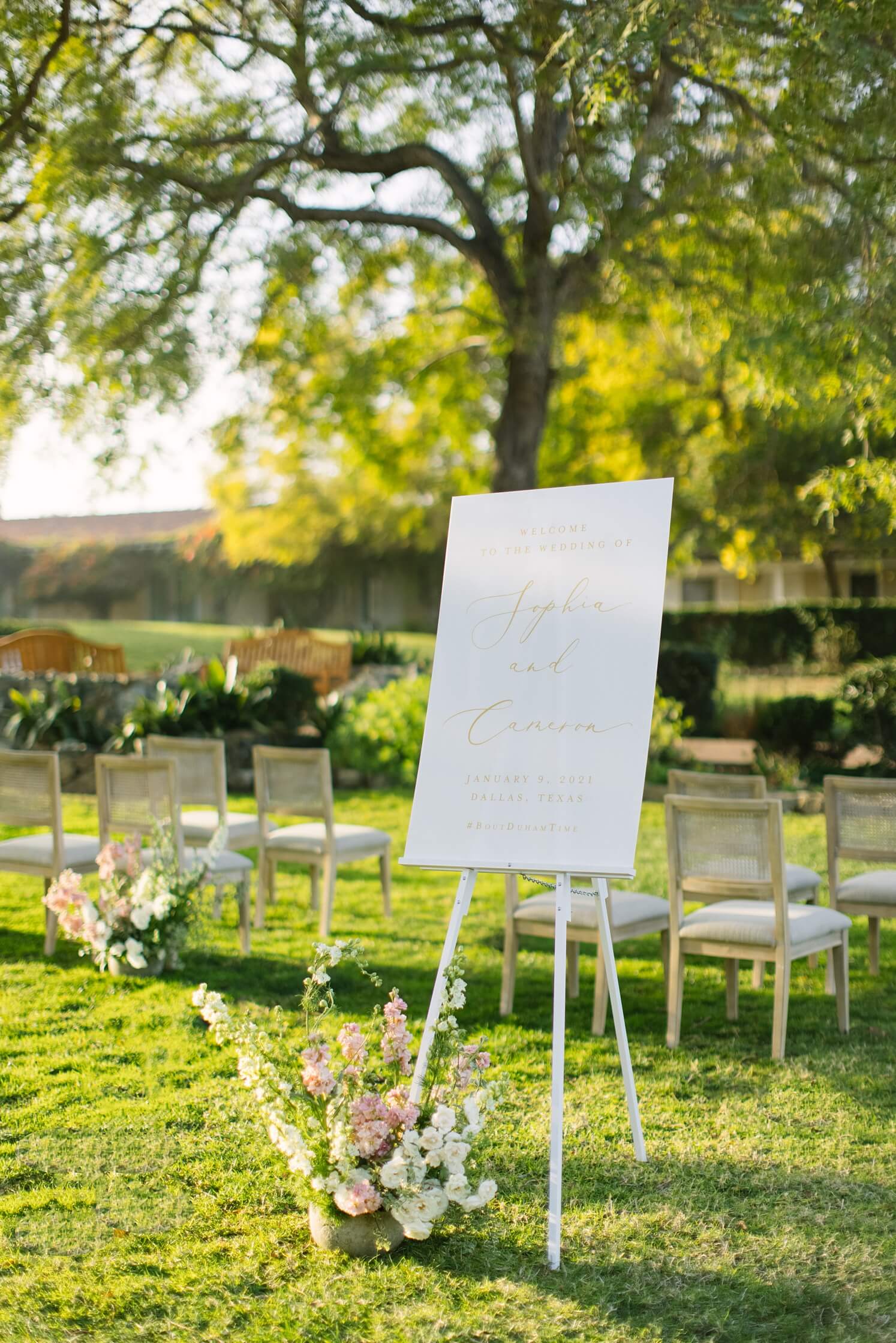 Wedding signs checklist: White welcome wedding sign with gold font with flowers at the base | McArthur Weddings and Events