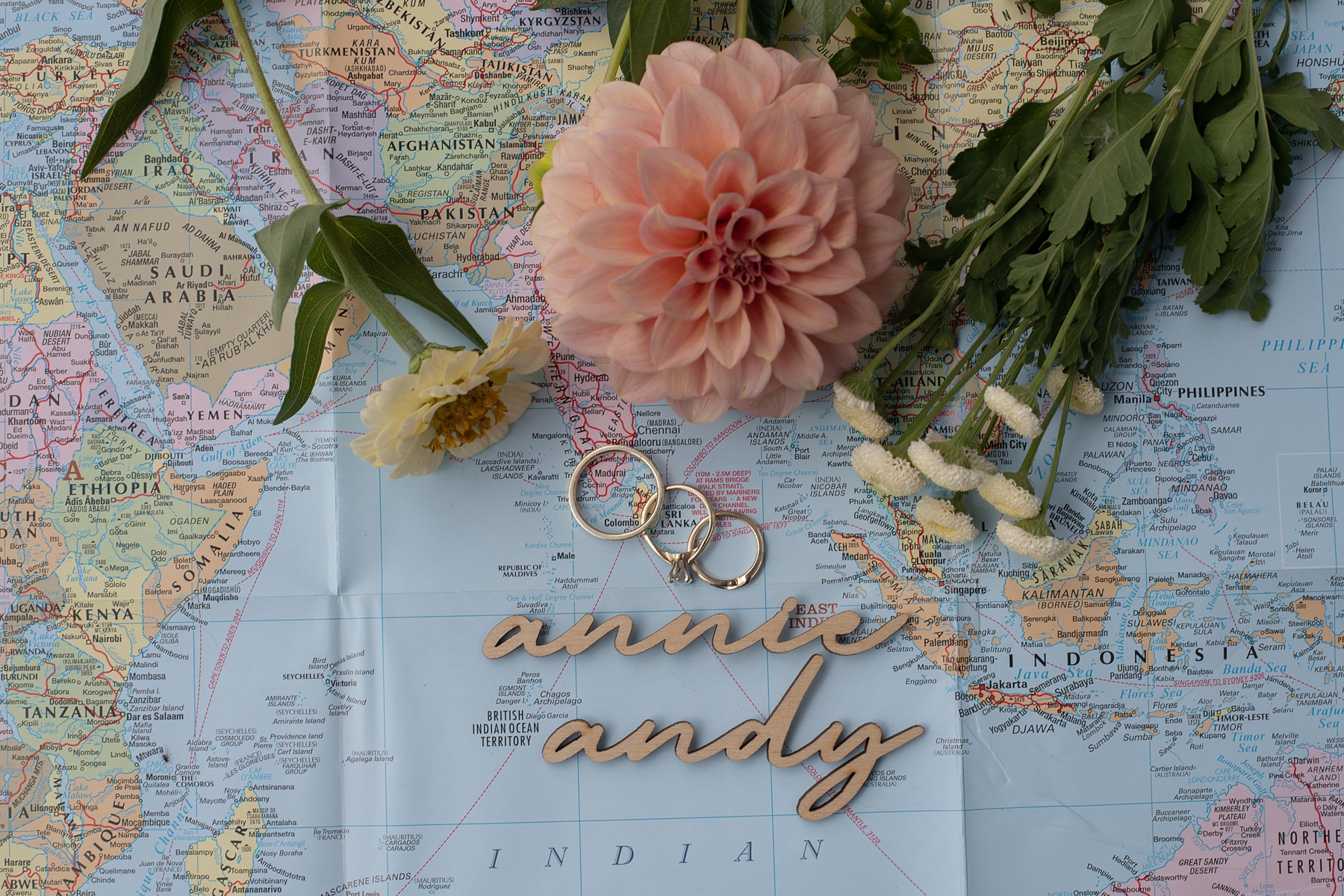 Bride and groom's ring on top of map with pink dahlia 