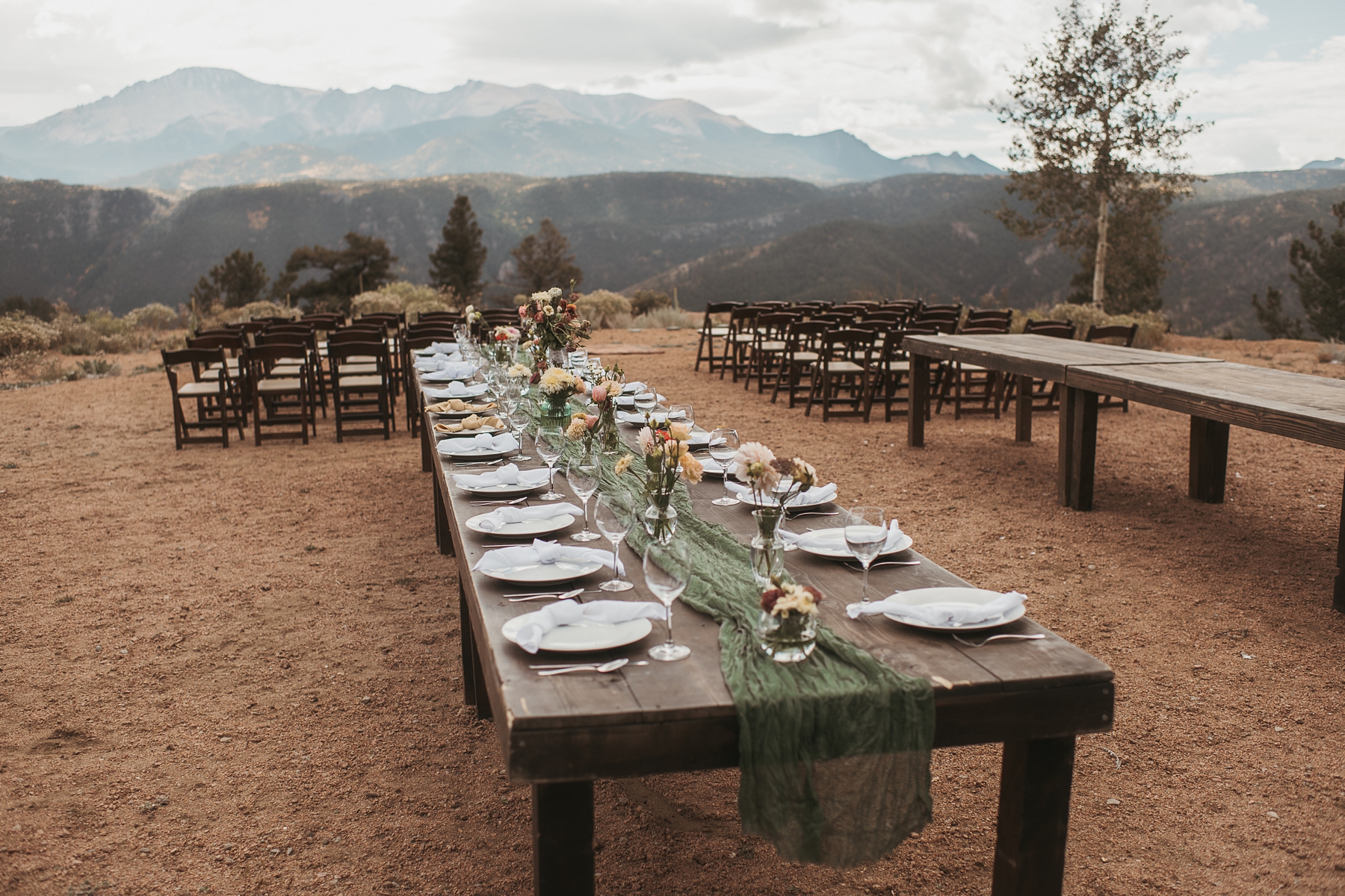 Farm house table with green runner and cream and pink flowers with mountains in the background 