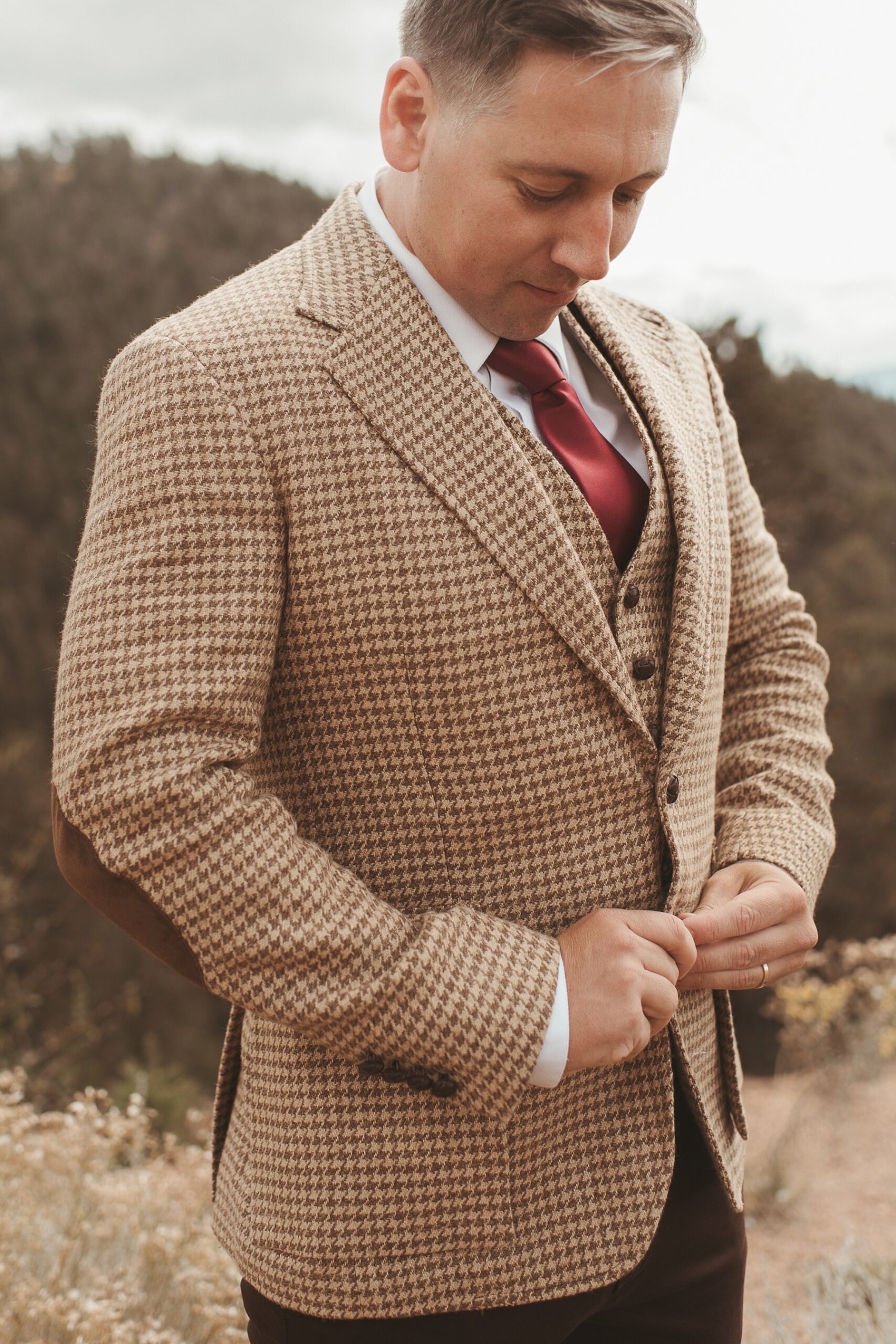 Groom buttoning tan houndstooth jacket