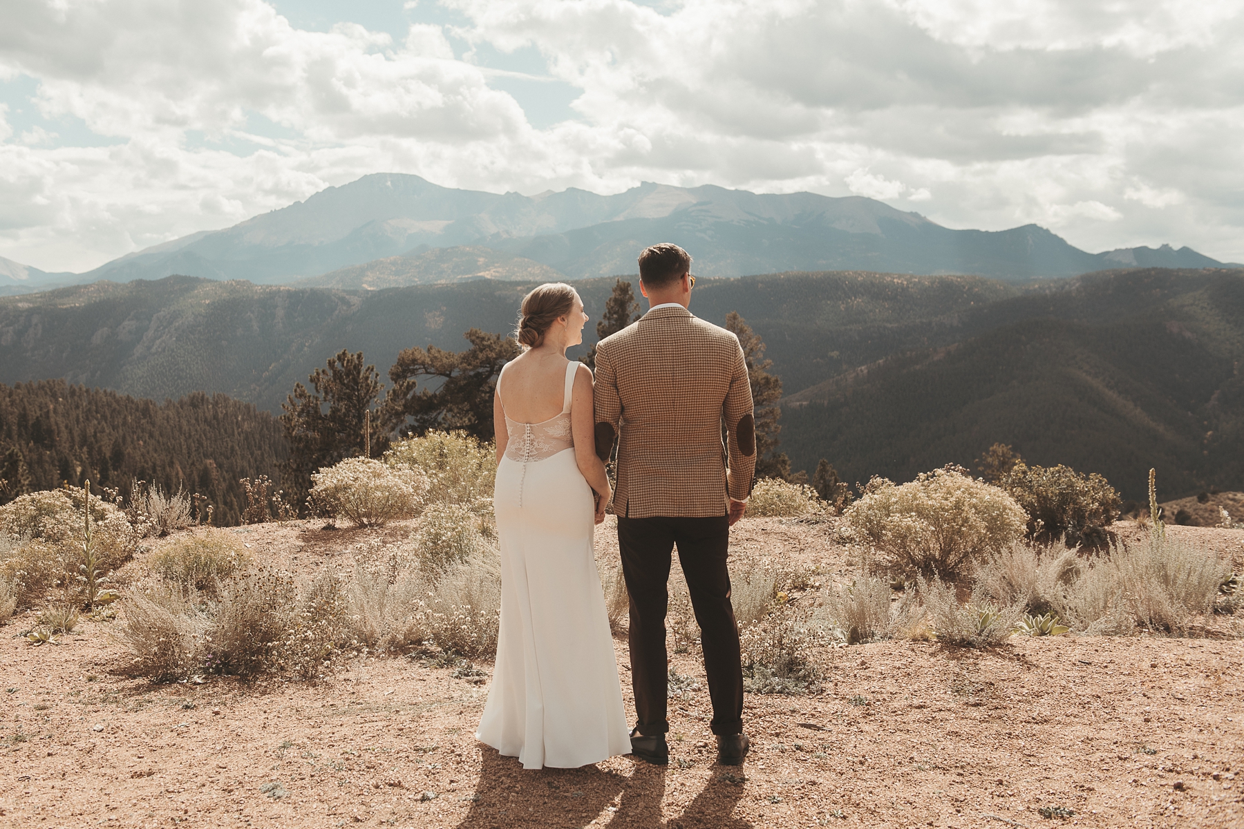 Bride and groom holding hands and looking out at mountains at Airbnb wedding venue in Colorado
