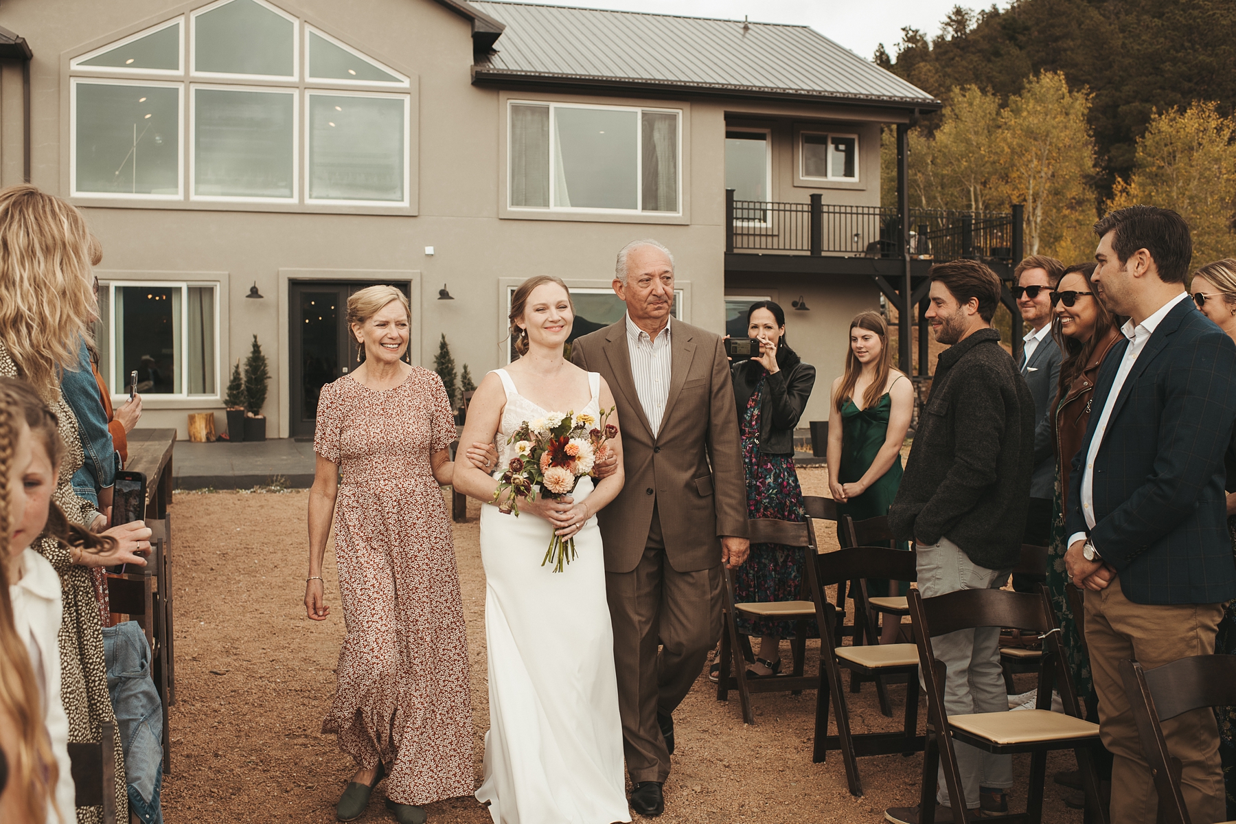 Bride walking down the aisle with her parents at Airbnb wedding venue in Colorado