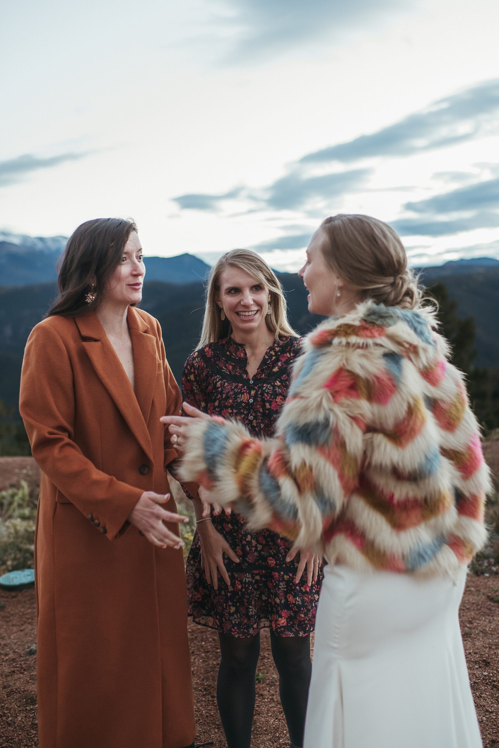 Bride talking to friends in colorful fur coat at Airbnb wedding venue in Colorado