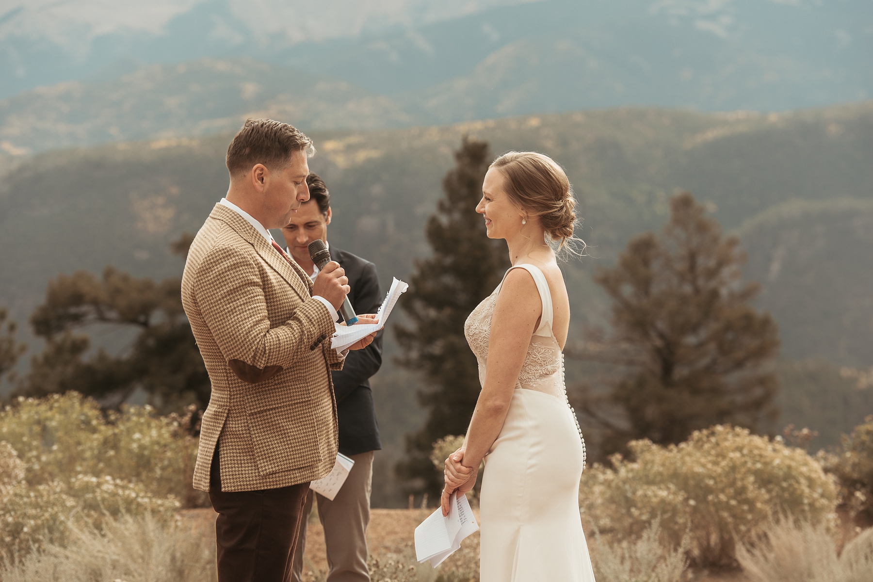 Groom saying vows to bride in front of mountains 