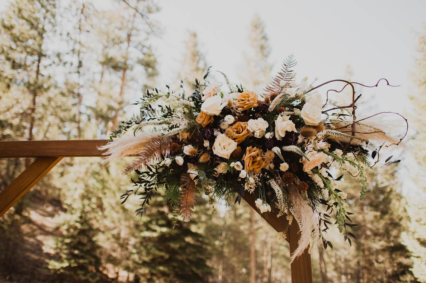 Boho floral installation on ceremony arch at Evergreen wedding venue | McArthur Weddings and Events