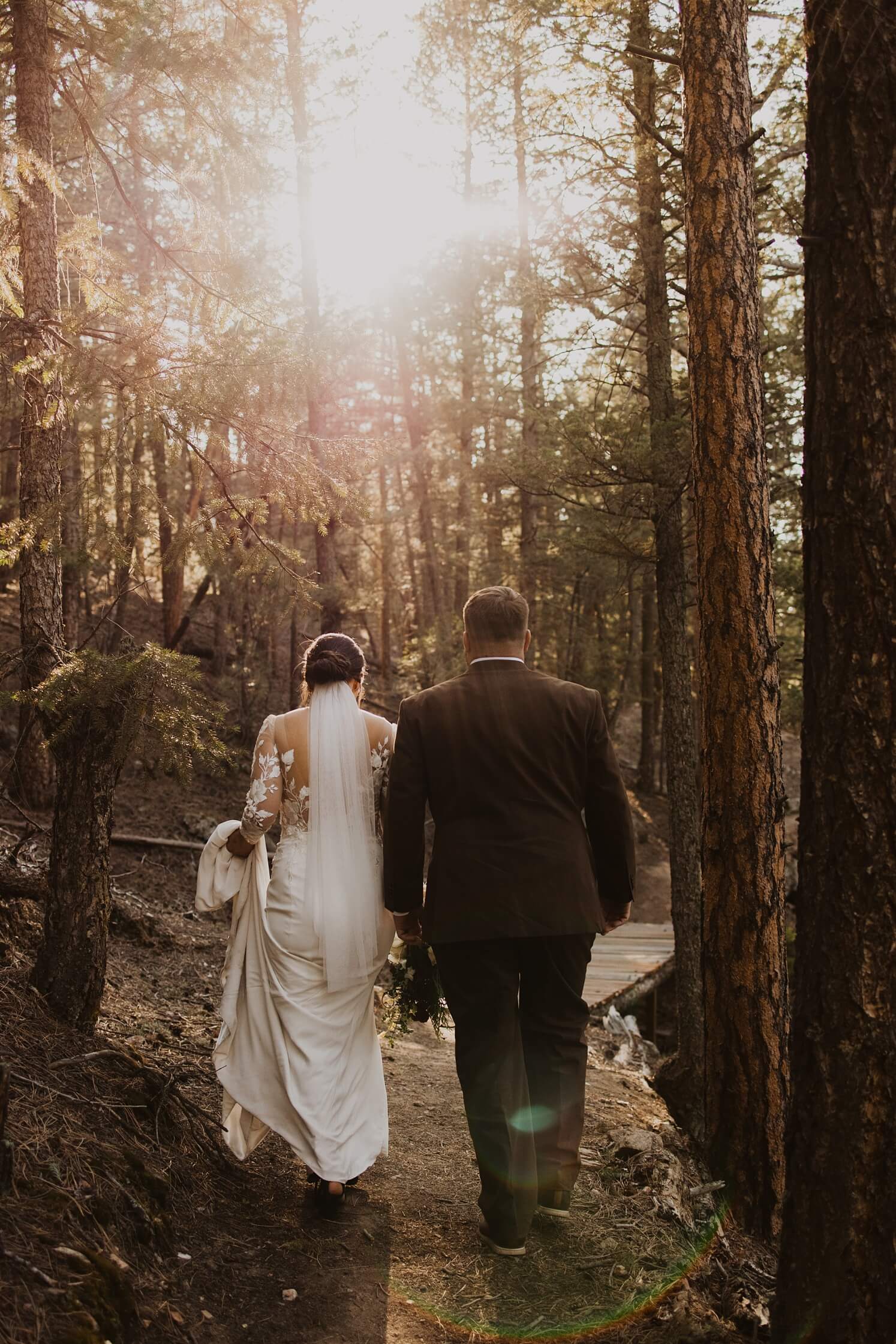 Bride and groom walking through forest at Evergreen wedding venue | McArthur Weddings and Events