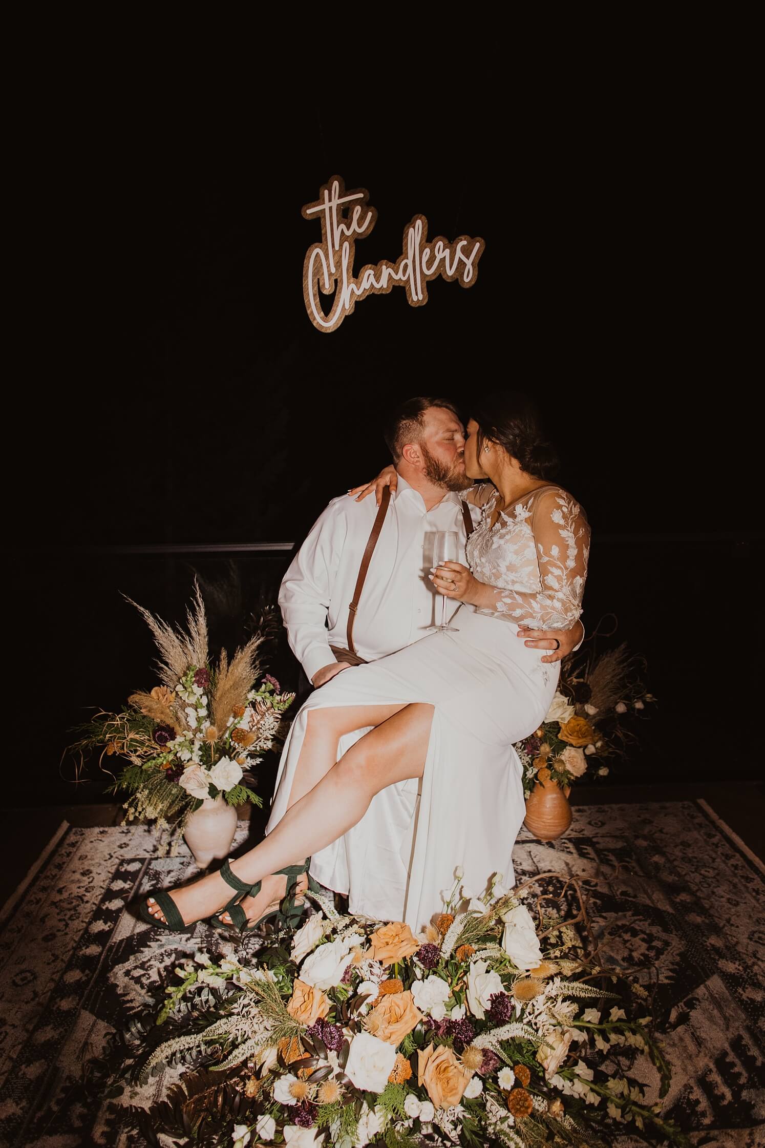 Bride and groom kissing in front of neon sign at Evergreen wedding venue| McArthur Weddings and Events