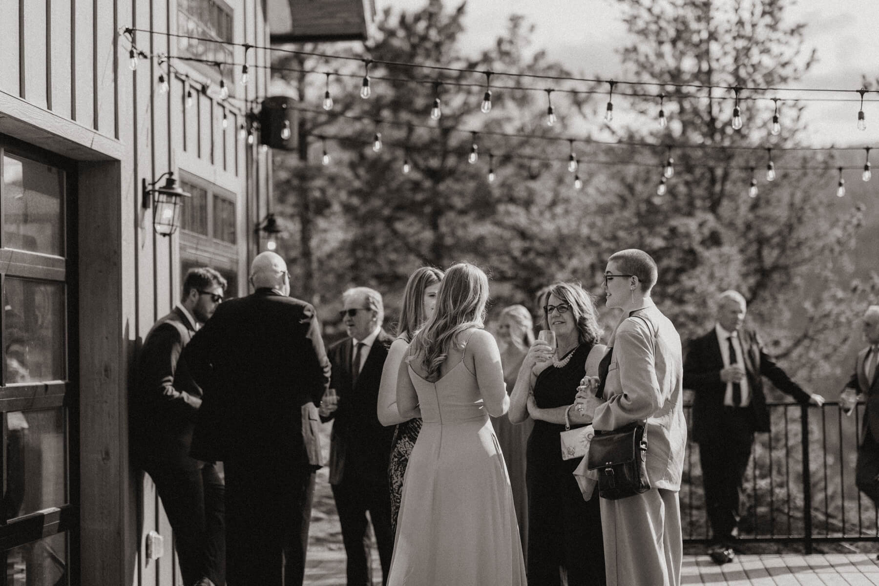 Wedding guests standing outside talking during cocktail hour in post about plus ones at weddings | McArthur Weddings and Events