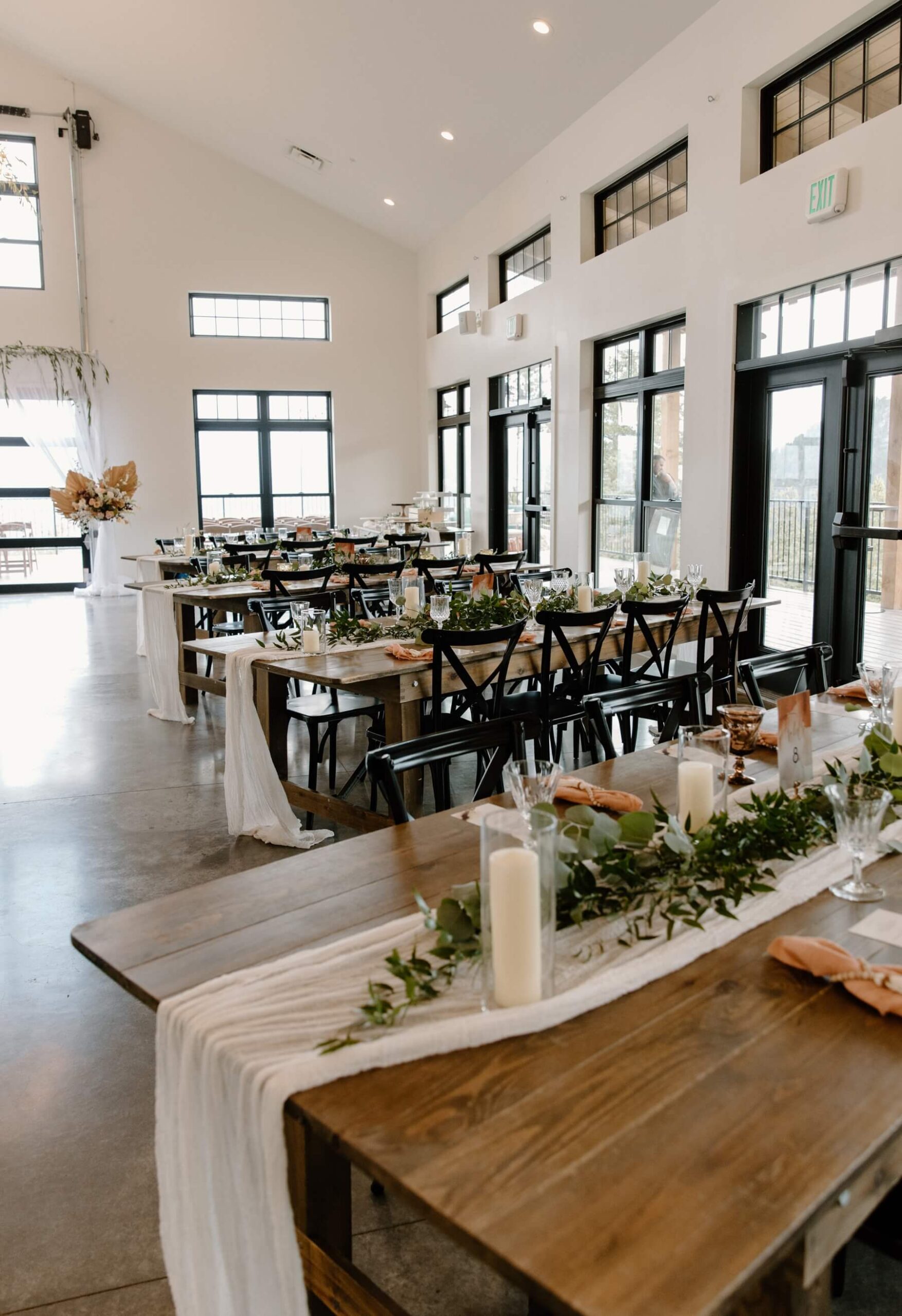 Farmhouse tables with black cross back chairs and white runners at Idaho Springs wedding venue | McArthur Weddings and Events