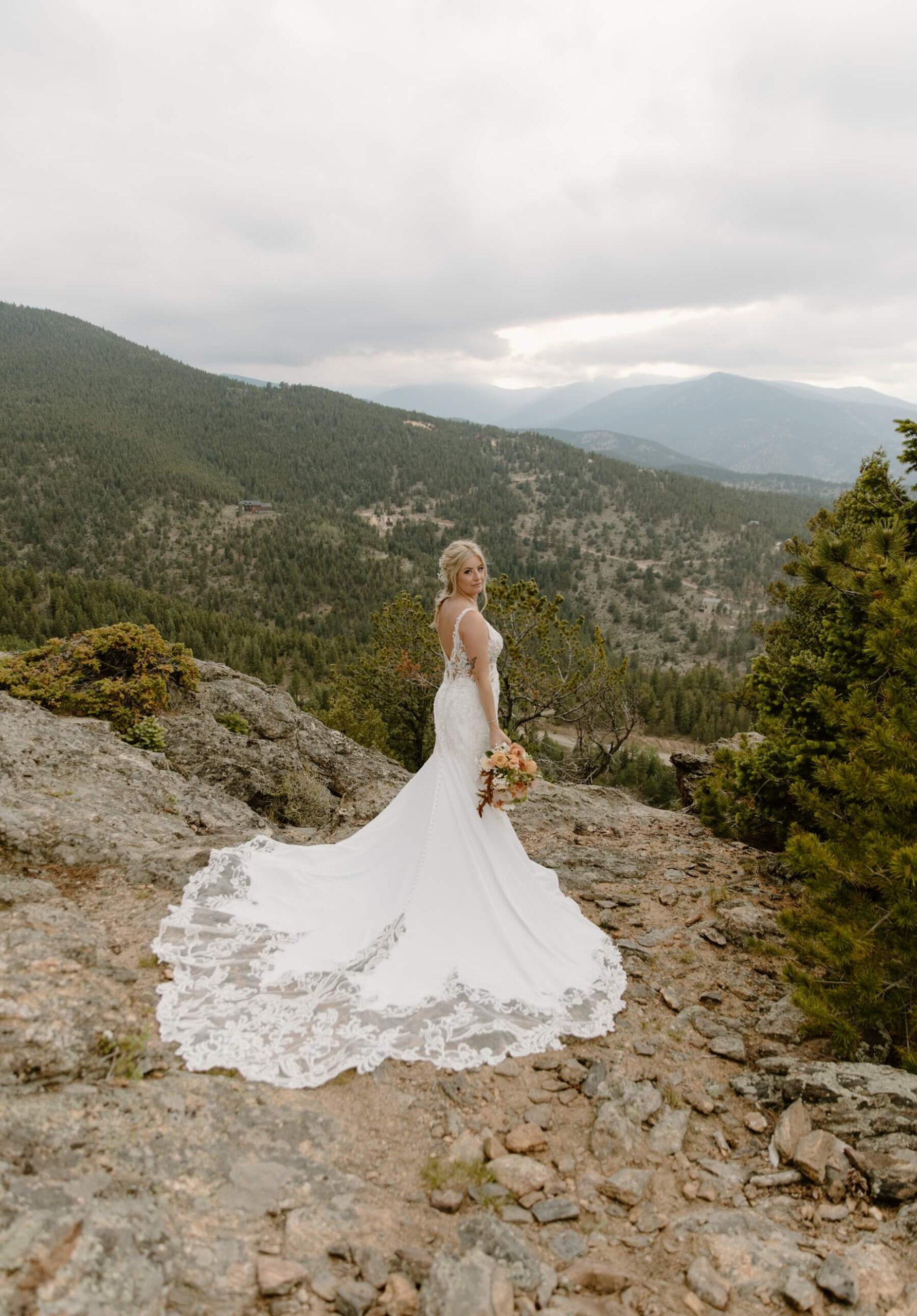 Bride with train extended behind her standing in front of mountains at idaho springs wedding venue | McArthur Weddings and Events