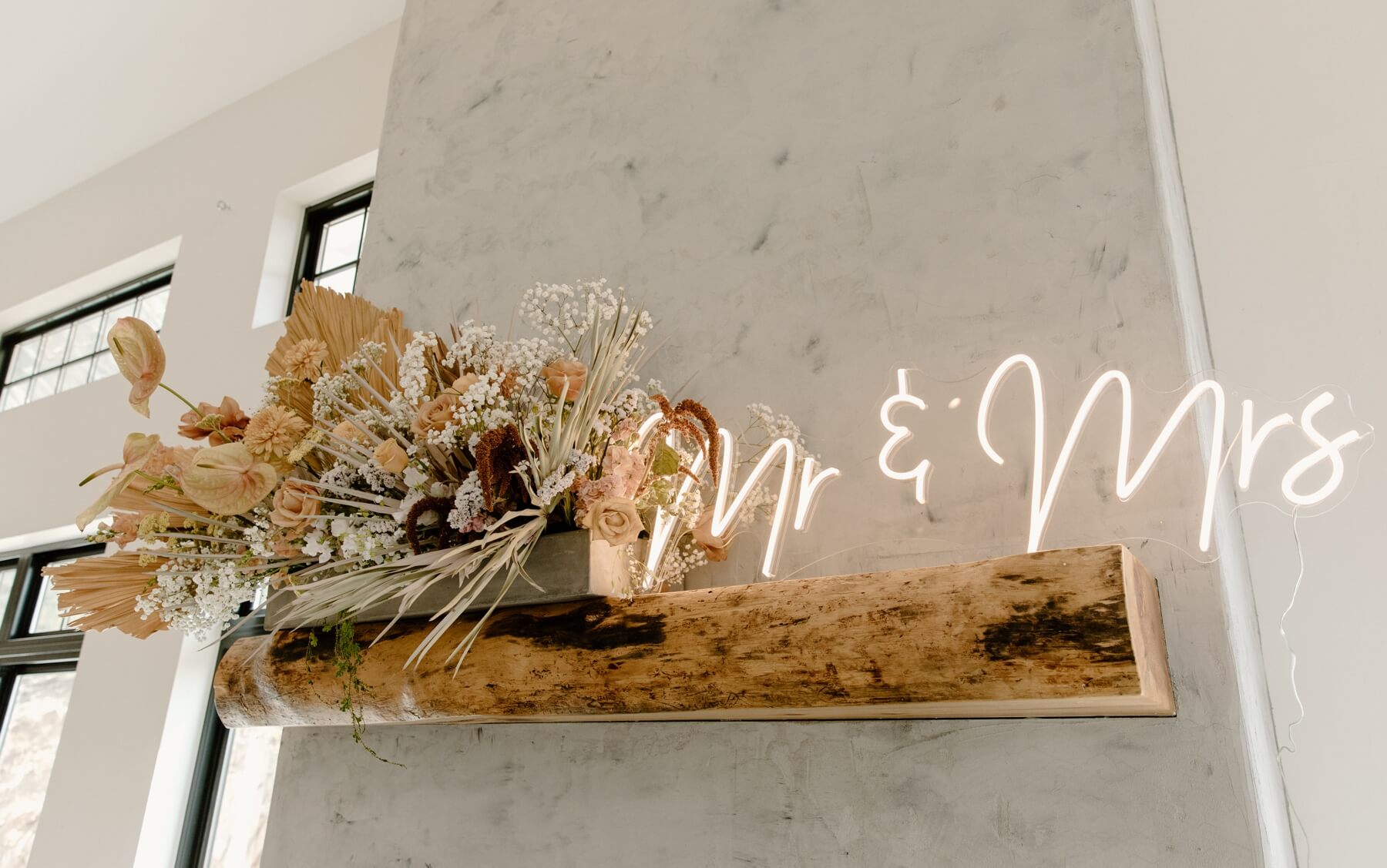 Boho floral arrangement on mantle with neon sign at idaho springs wedding venue | McArthur Weddings and Events