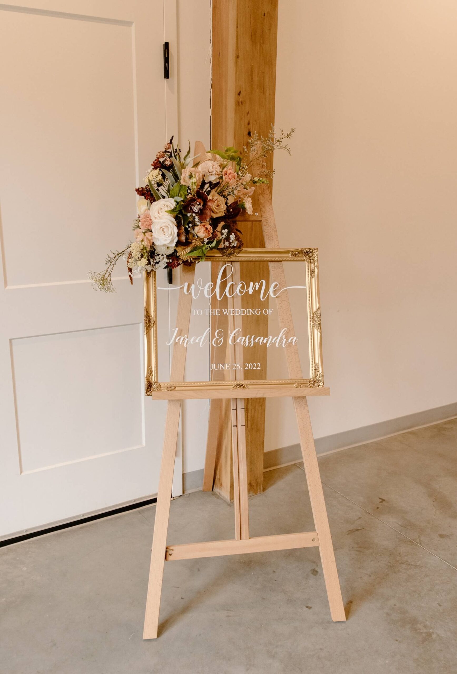 Acrylic welcome sign framed by gold frame with boho floral arrangement at idaho springs wedding venue | McArthur Weddings and Events